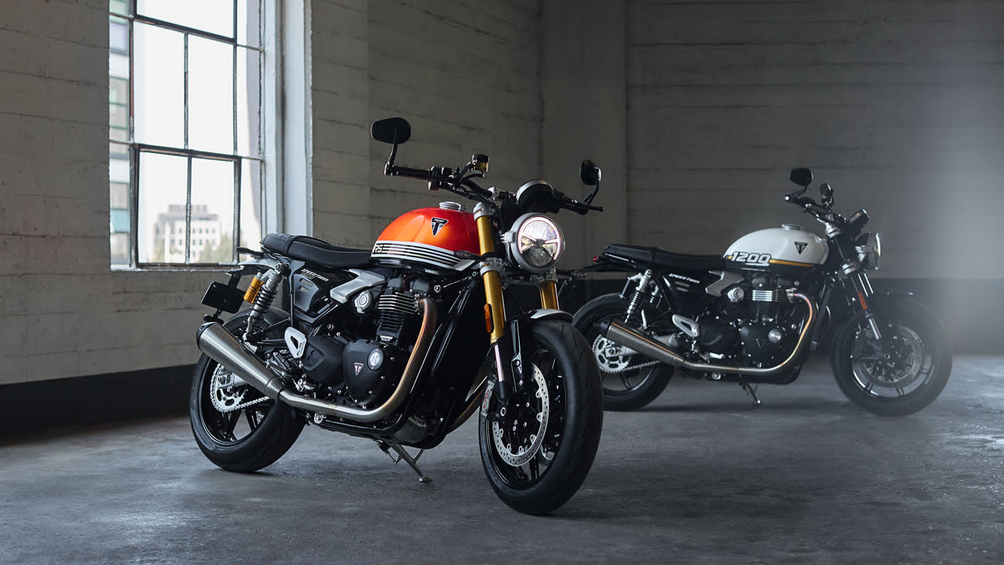Triumph Speed Twin 1200 and RS riding indoors parked next to a window