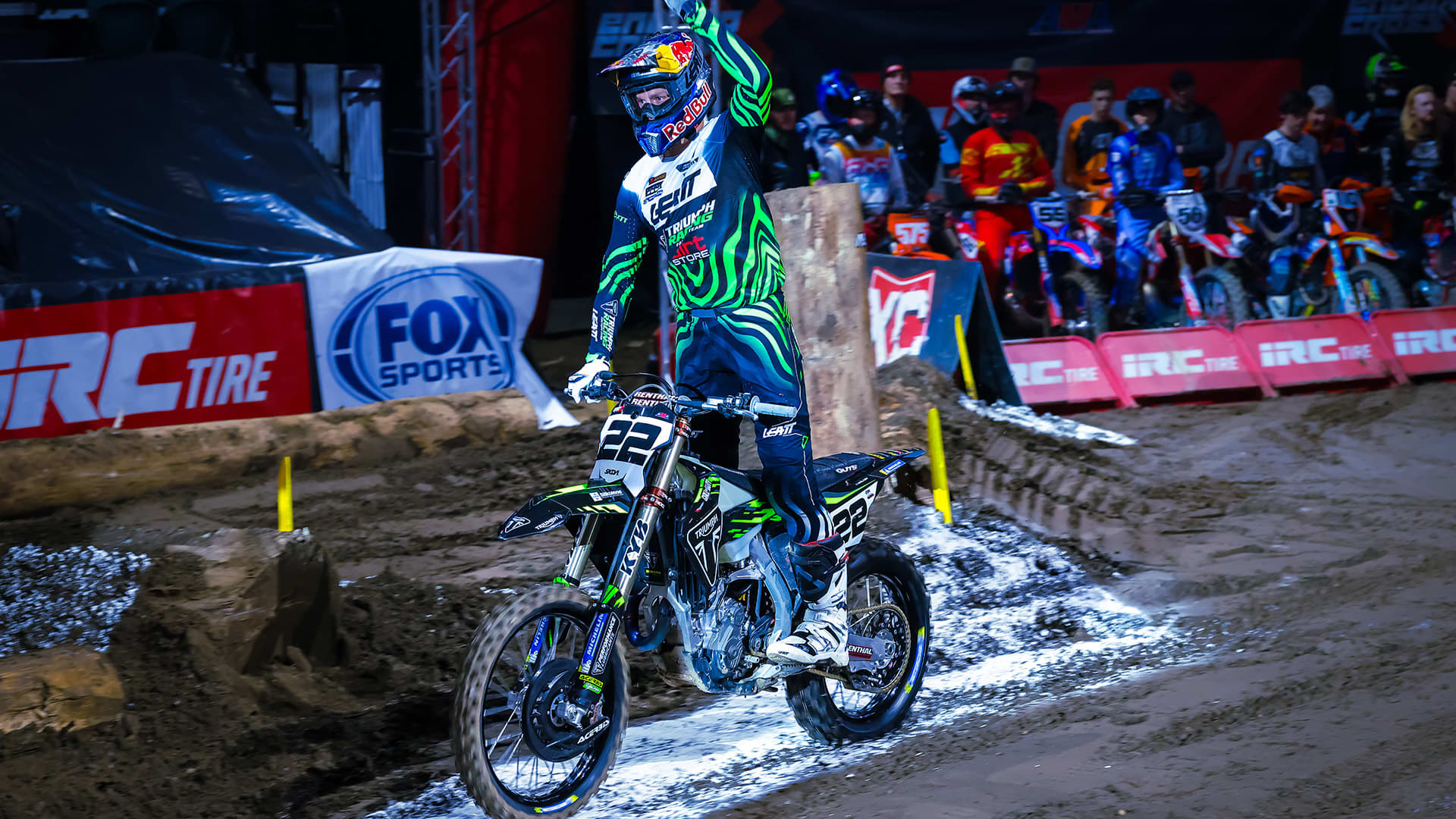 Jonny Walker standing on foot rests of Triumph 450-E with his hand in the air