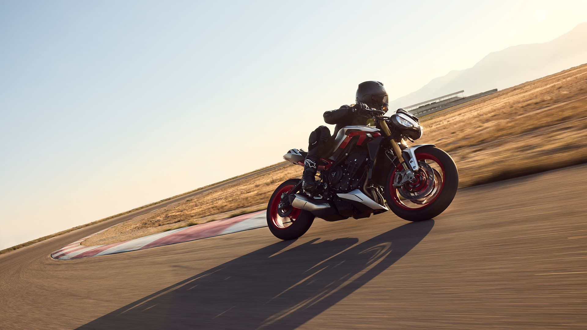 Side view of a rider on the Triumph Street Triple RX riding on a track