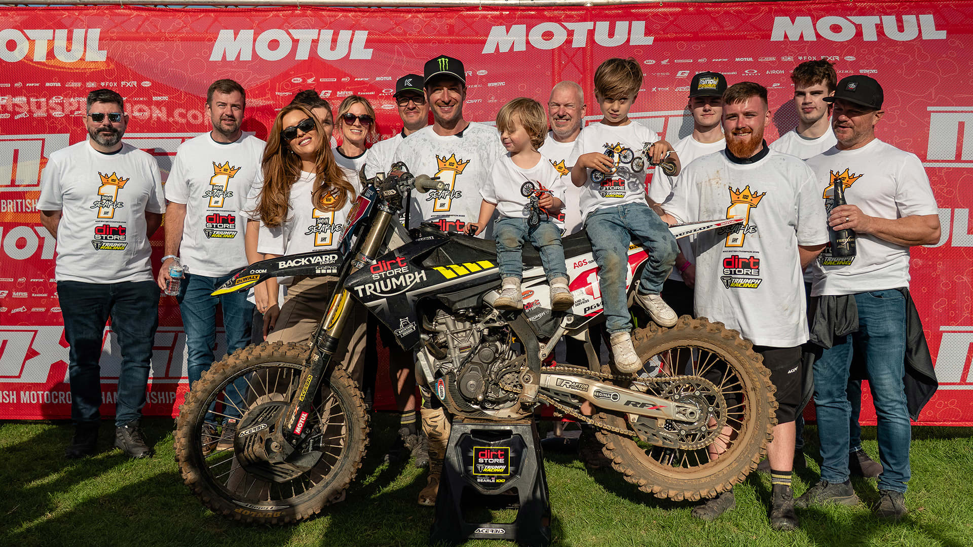 Group of people surrounding Triumph racing motorcycles