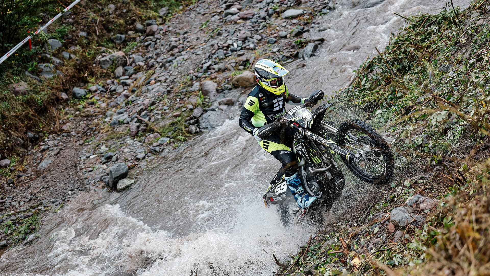 Man riding Triumph TF 250-E up a steep muddy hill at Enduro