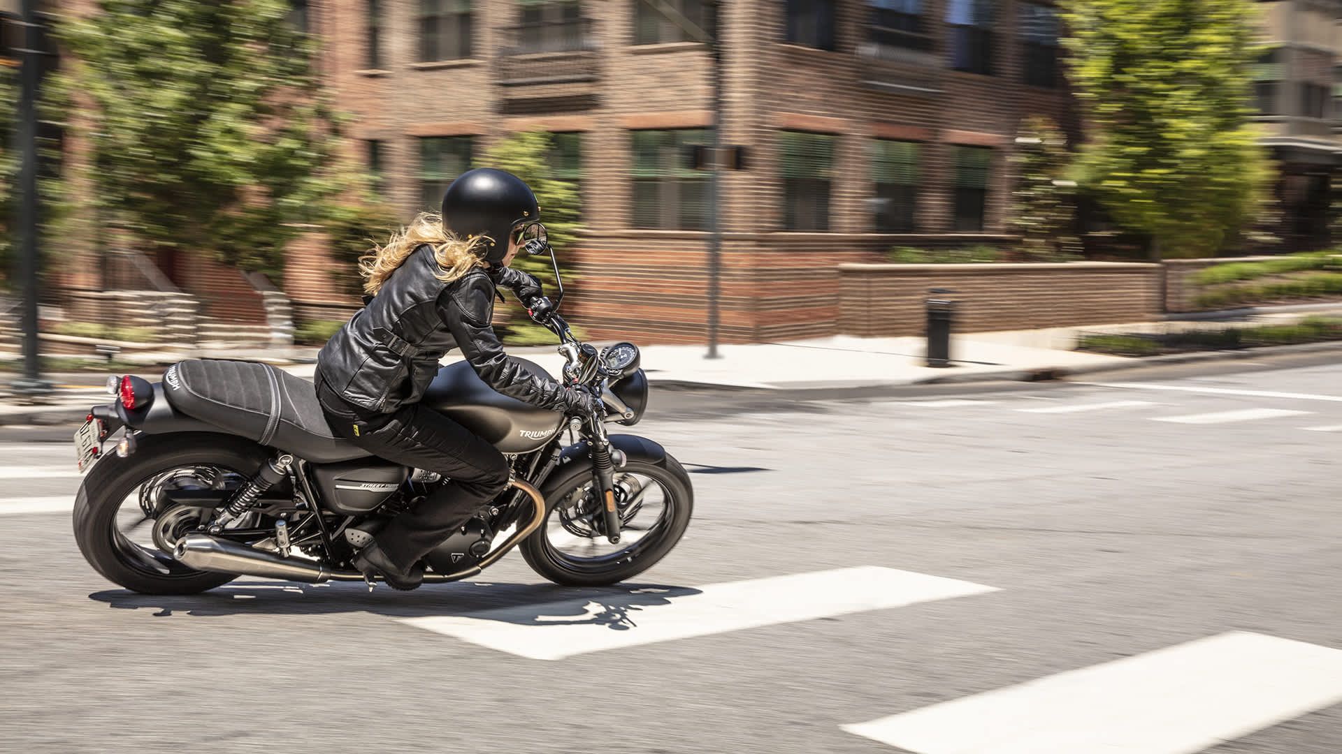 Woman riding through street on a Street Twin
