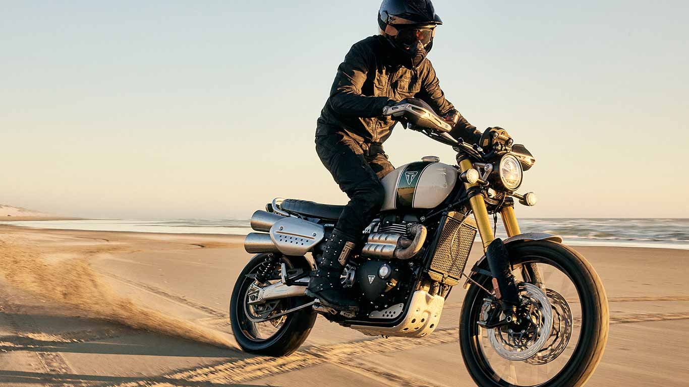 Triumph Scrambler 1200 XE being ridden along a beach