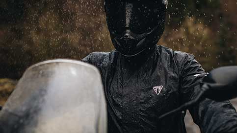 A woman riding in the rain wearing a Triumph waterproof Storm Guard jacket