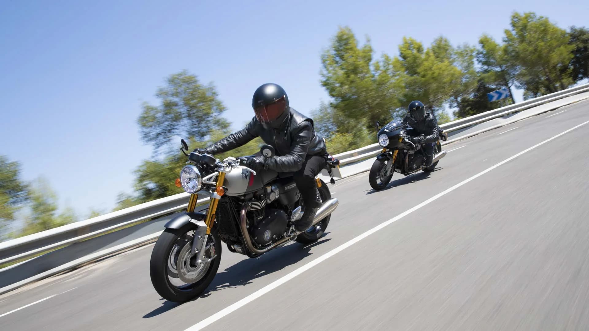  Action shot of Triumph Thruxton RS motorcycles riding down a road together