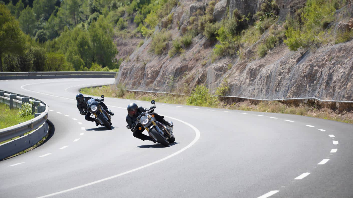 Action shot of two new Triumph Thruxton RS motorcycles flowing through mountainous corners