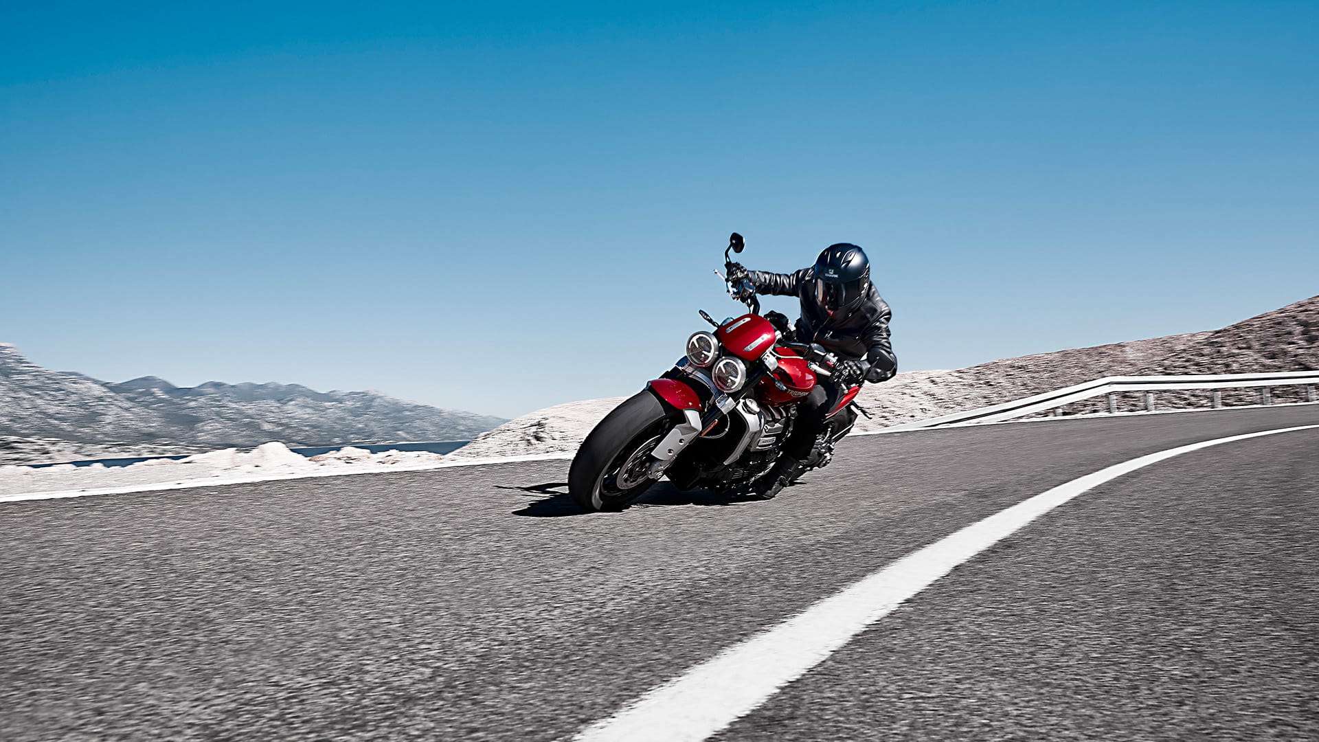 A rider cornering a scenic route on the new Triumph Rocket 3 R in Korosi Red