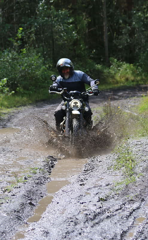 A rider on Triumph Scrambler 1200 crossing through muddy water and tough terrain