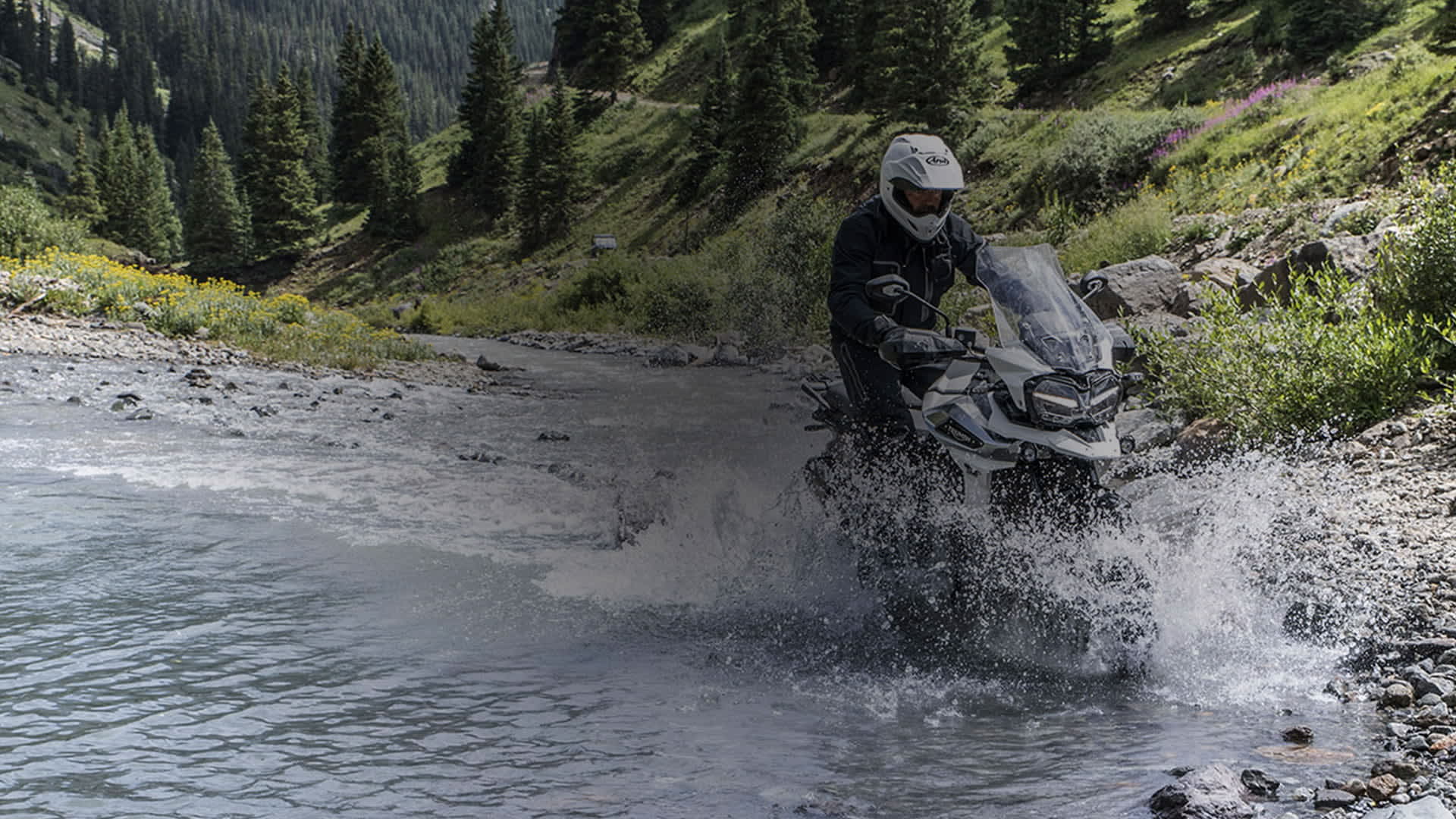 Person riding a Tiger 1200 through a stream of water.