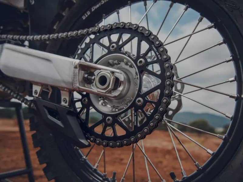 Close-up of the rear wheel, chain and sprocket on a Triumph off-road motorcycle.