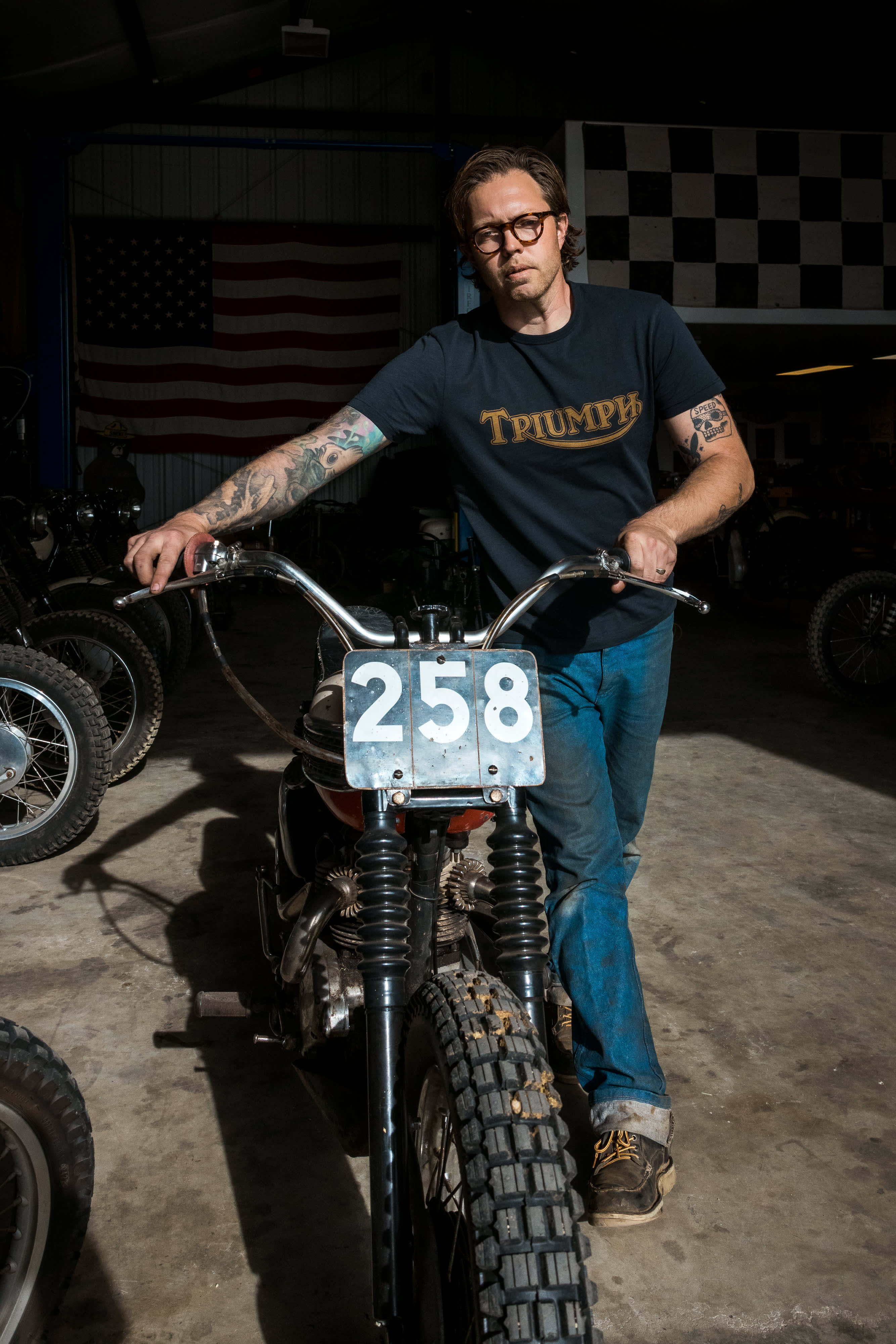 Man walking his Triumph Motorbike out of the garage wearing a Triumph Heritage T-Shirt
