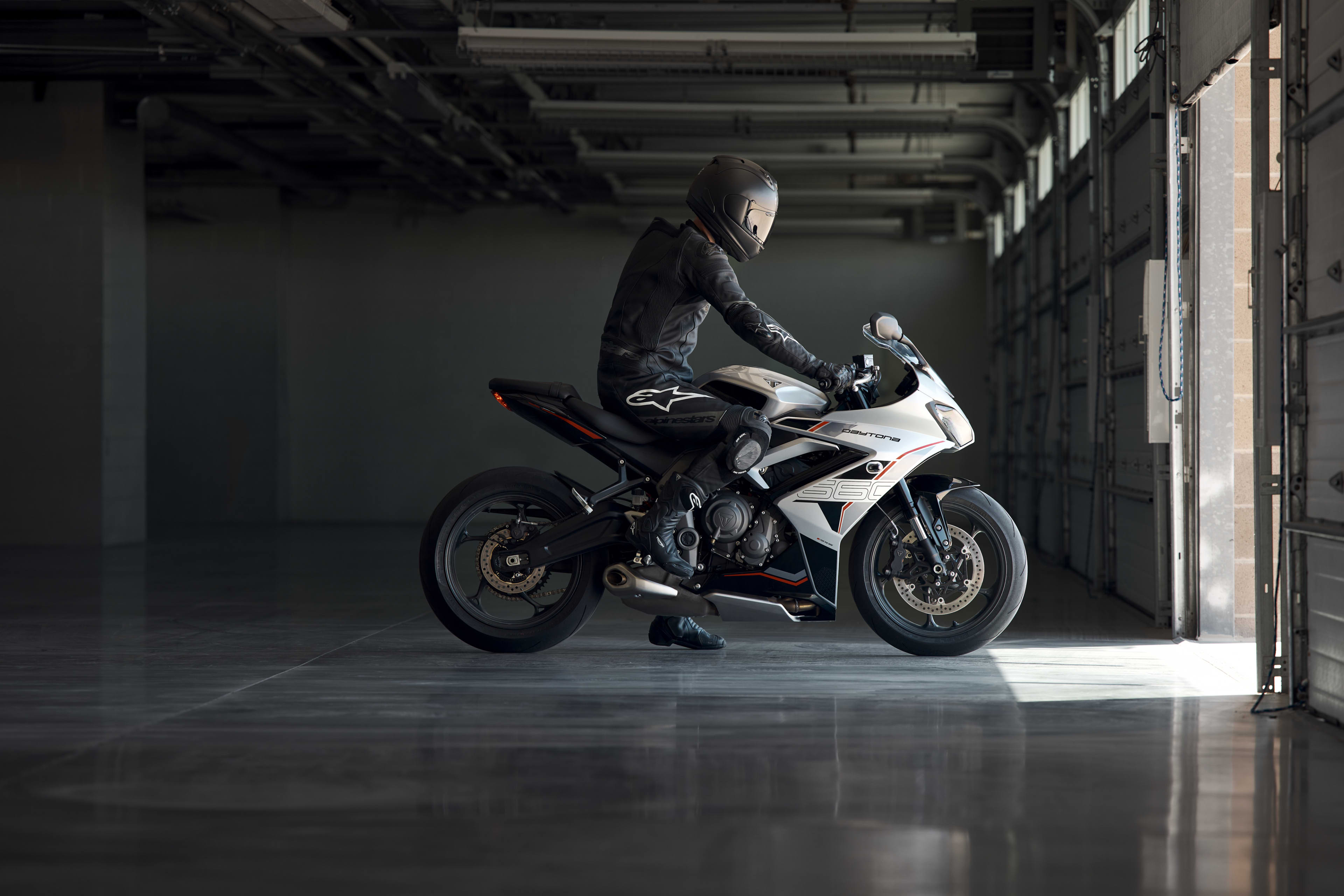 Right side view of rider sat on stationary Triumph Daytona 660