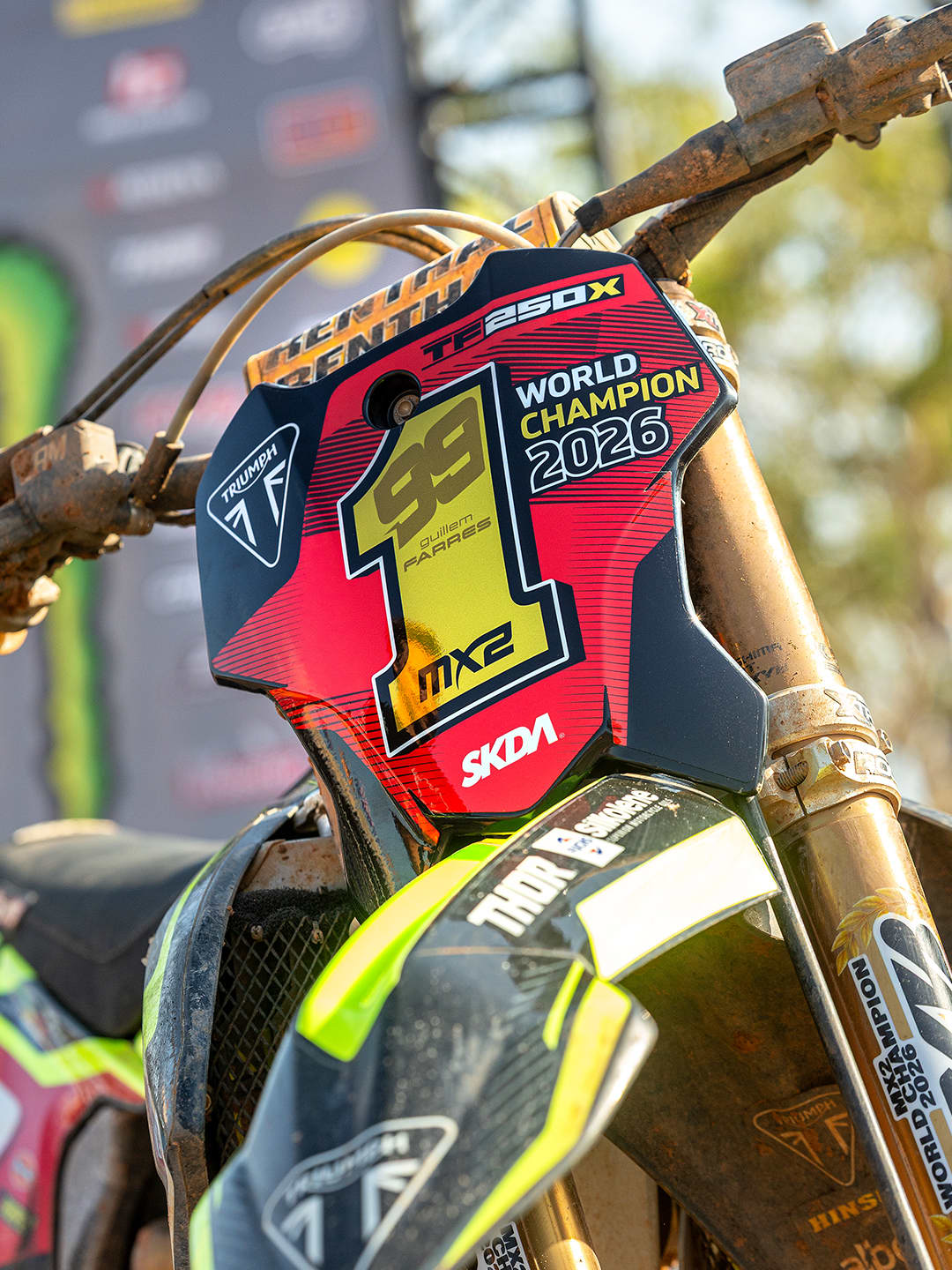 Triumph motocross racer leaning into a dirt-track corner.