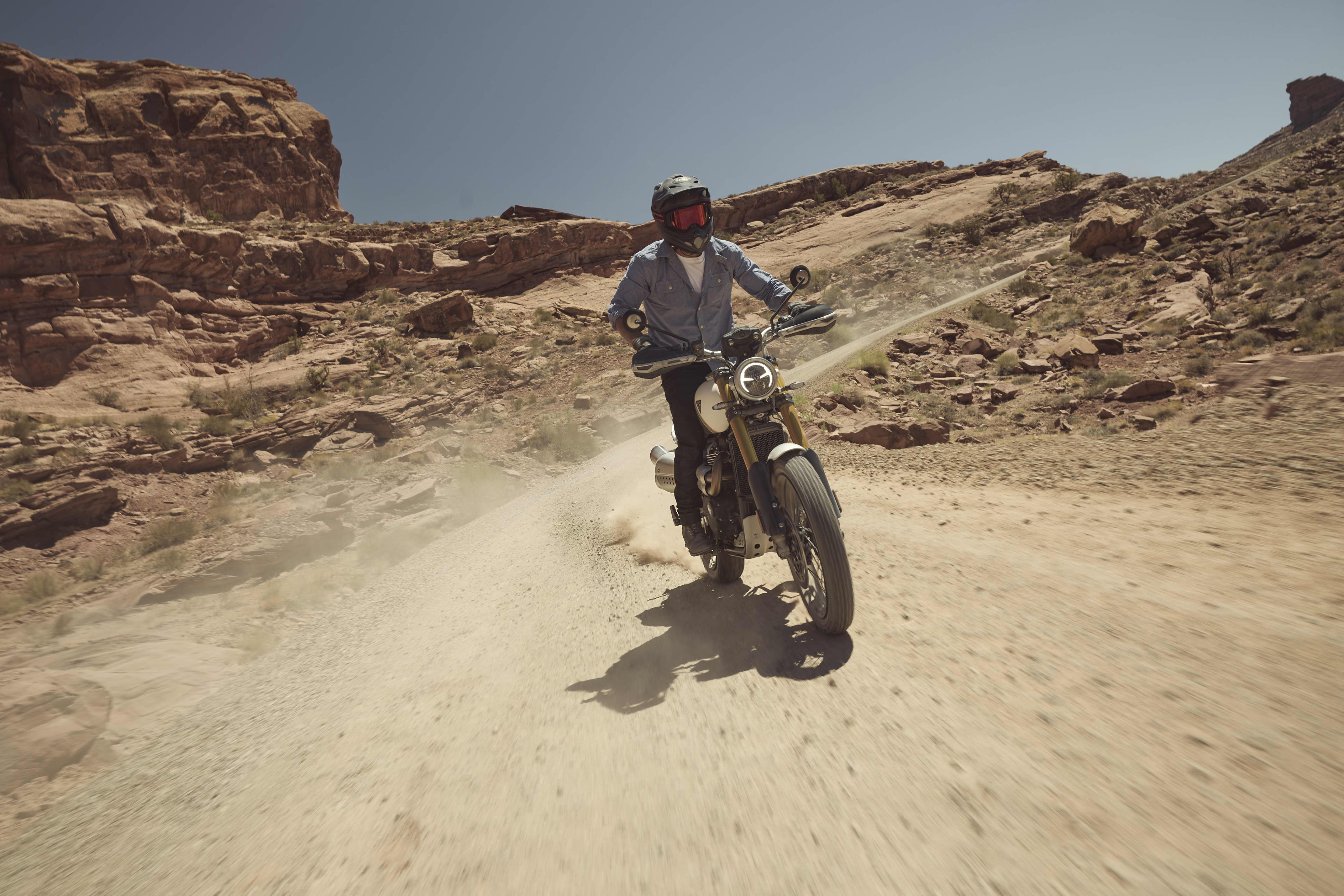 Front view of Triumph Scrambler 1200 XE cruising through a dirt track