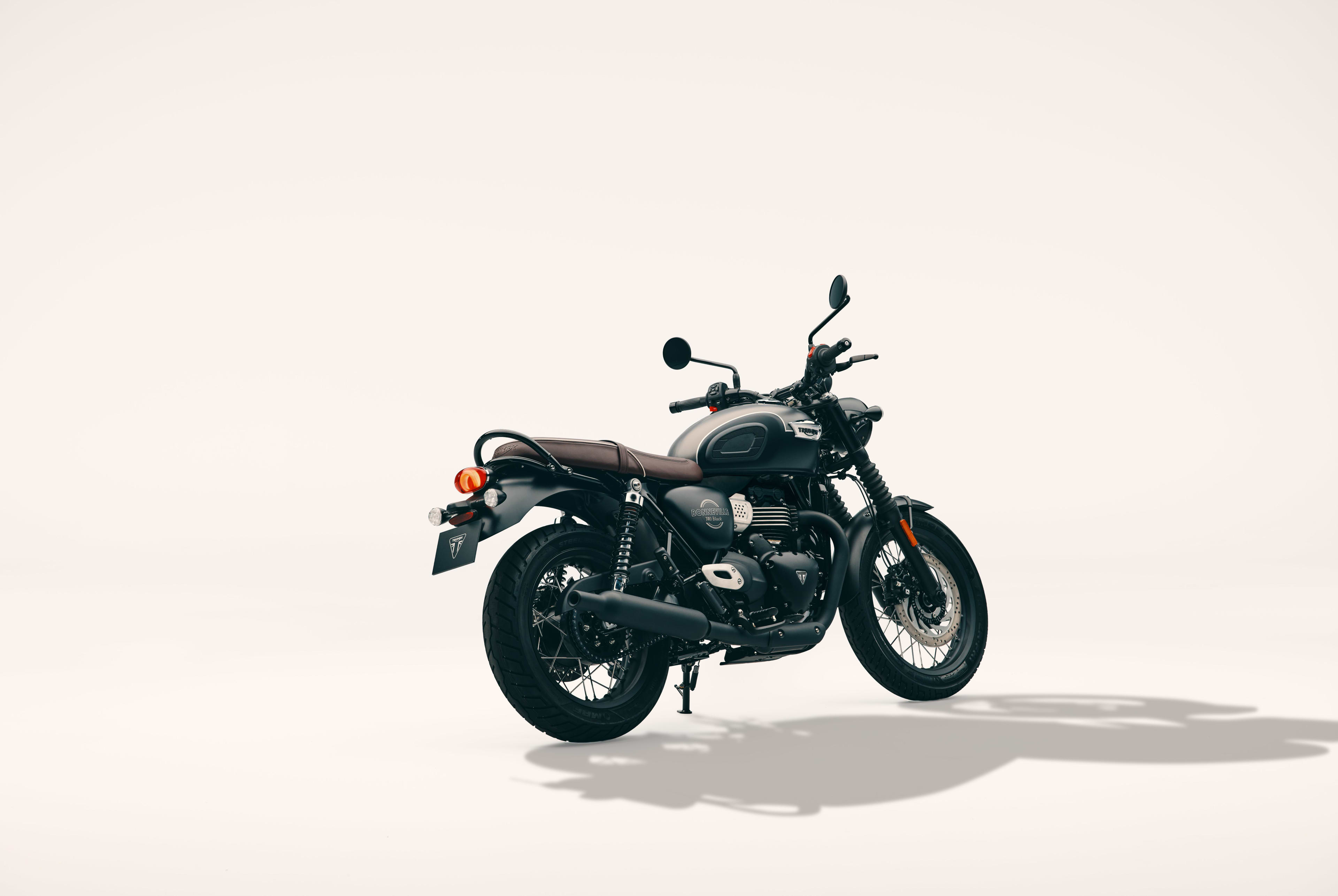 Rear three-quarter studio shot of a Triumph Bonneville T40 Black motorcycle with a satin grey and black tank on a light background.