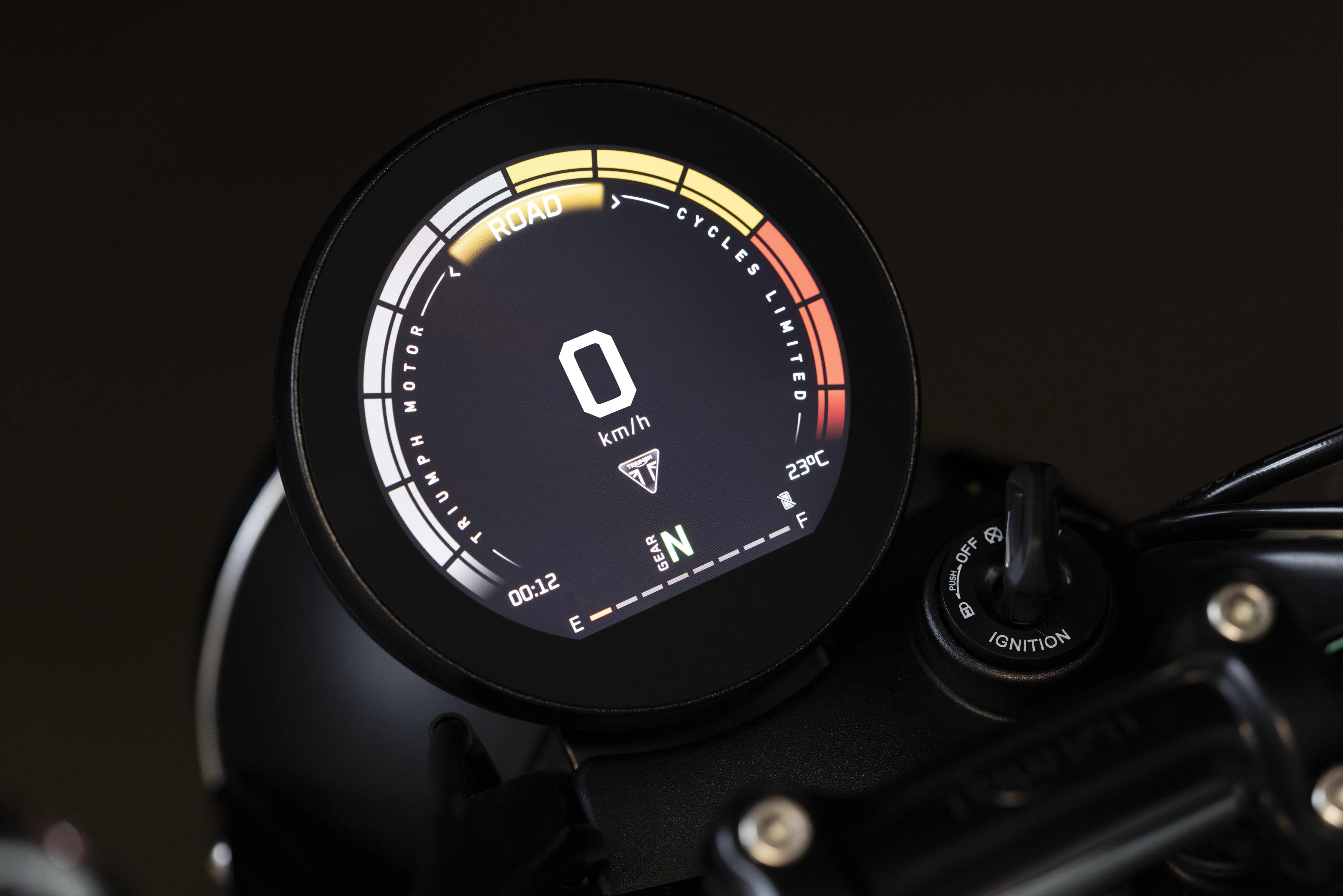 Close-up shot of the round digital TFT gauge display showing speed, neutral gear indicator, and mode on a Triumph motorcycle.