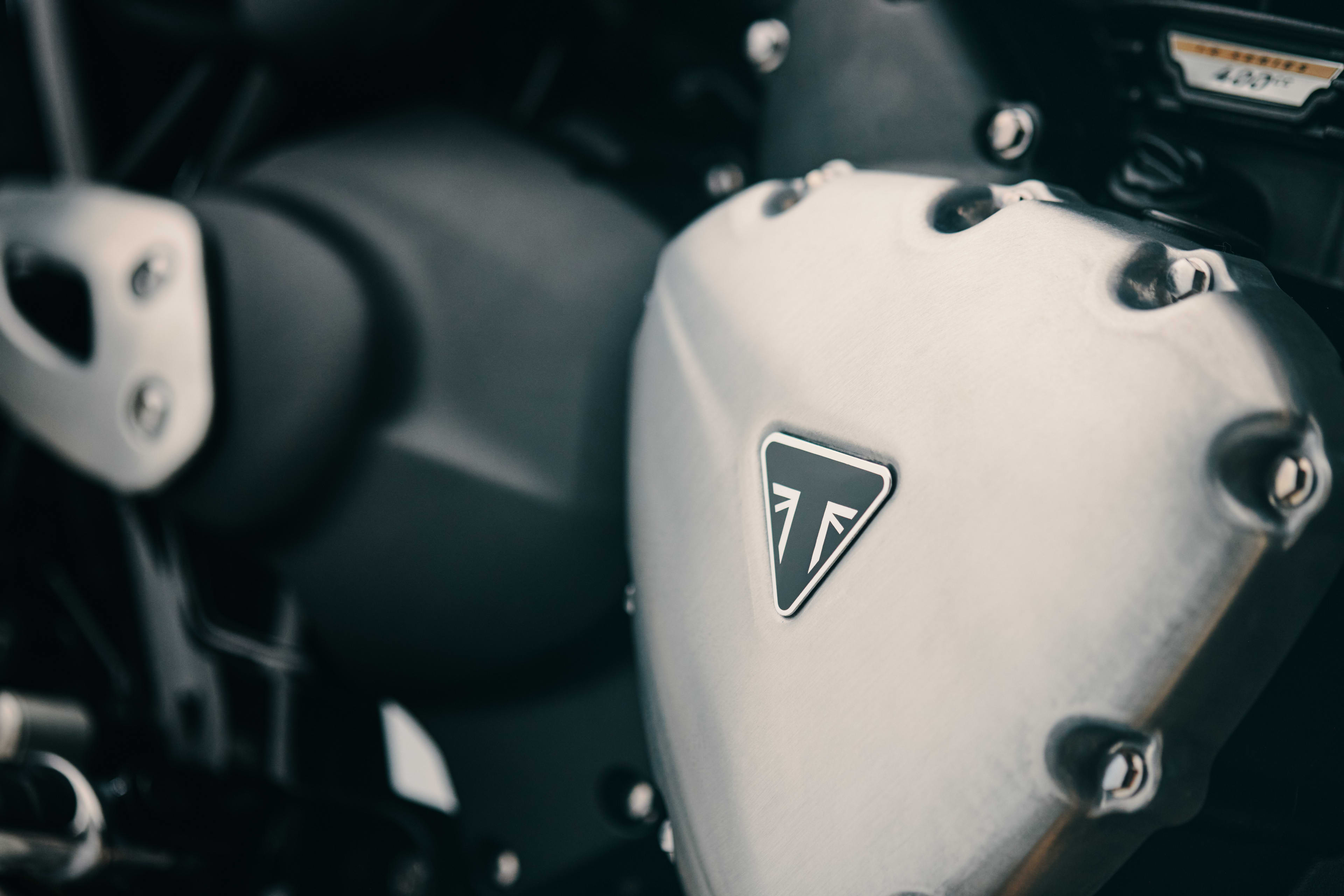 Detailed macro shot of a brushed aluminum engine casing featuring the black triangular Triumph logo on the Bonneville T40.