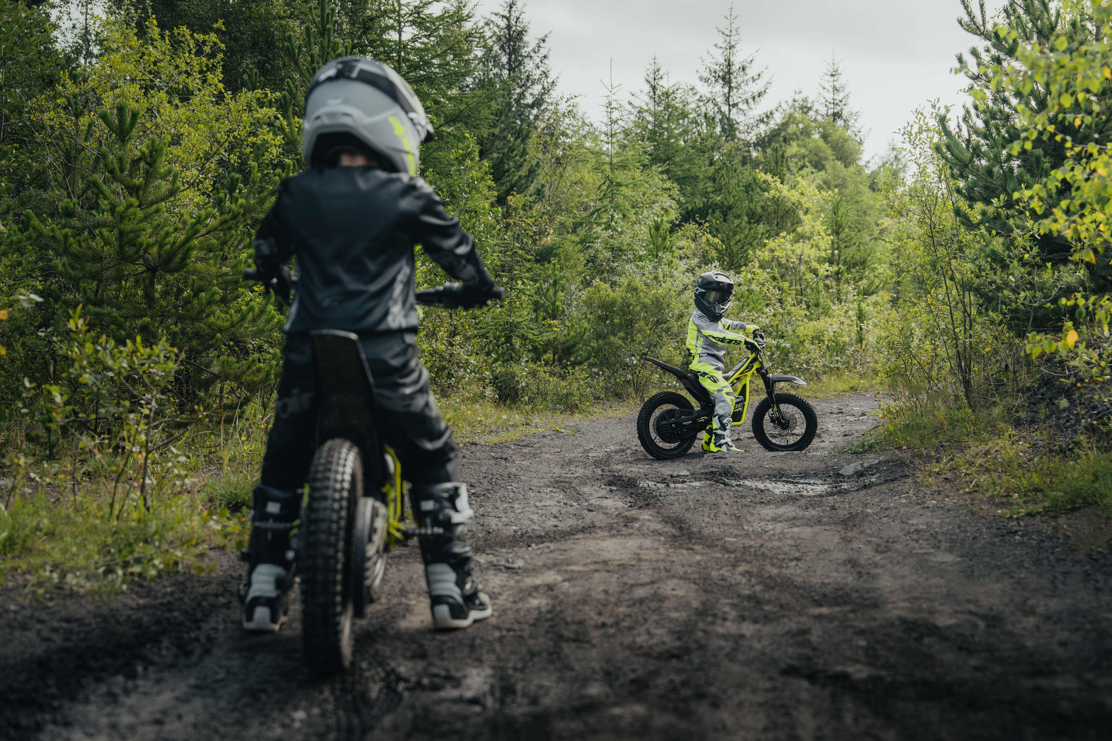 Young riders out riding on the Triumph TXP-16 in a forest trail.