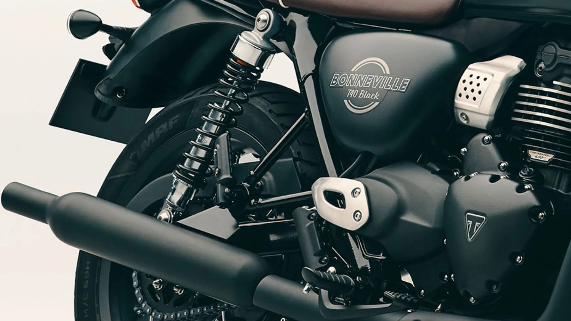 Close-up side profile showing the black bench seat, engine block, Bonneville T40 Black badge on a Triumph motorcycle.