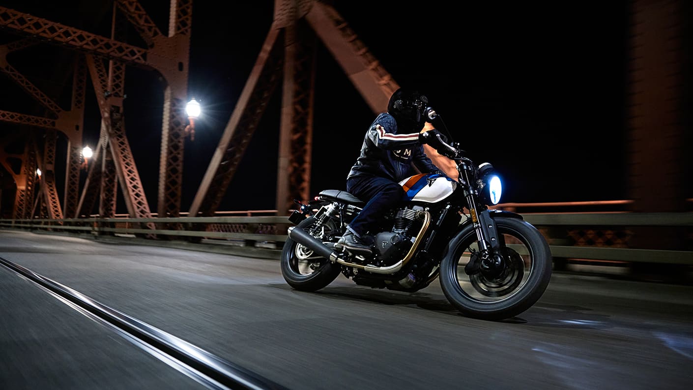 Right side view of a rider on Triumph Speed Twin 900 on a bridge at night