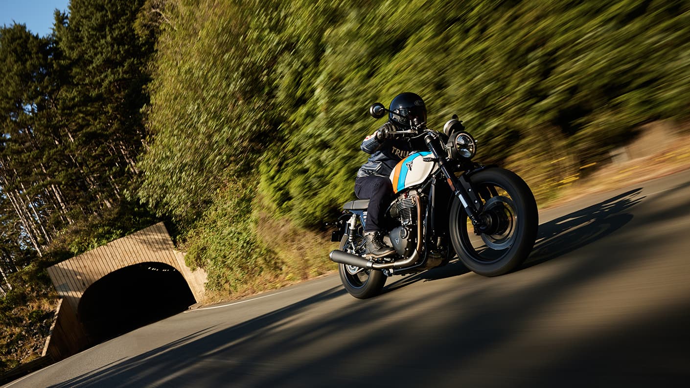 Right side angled shot of rider on Triumph Speed Twin 900 with trees in the background
