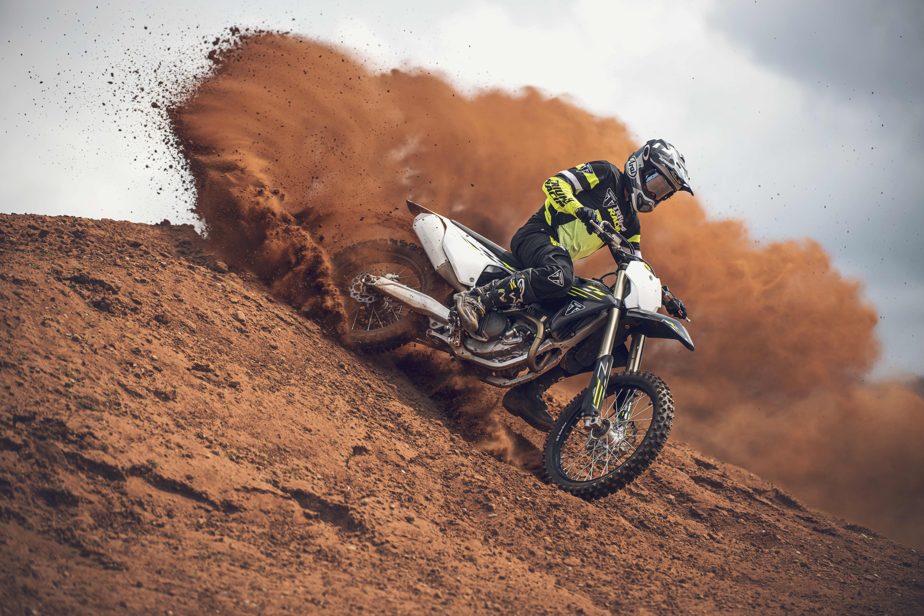 Triumph TF 250-X (MY26) side view riding downhill and spraying mud