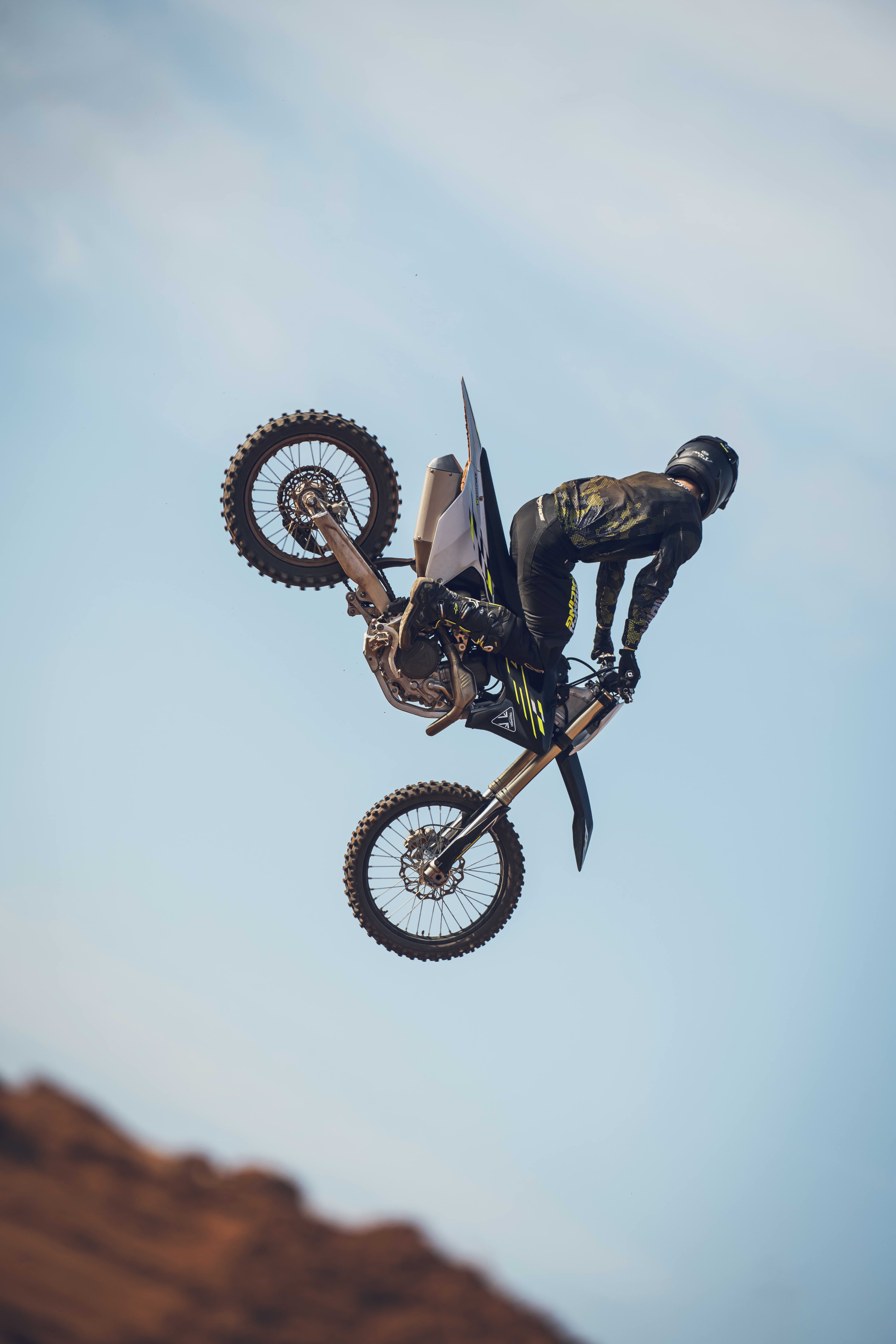 Side view of a Triumph TF 450-X (MY26) with rider airborne performing a stunt