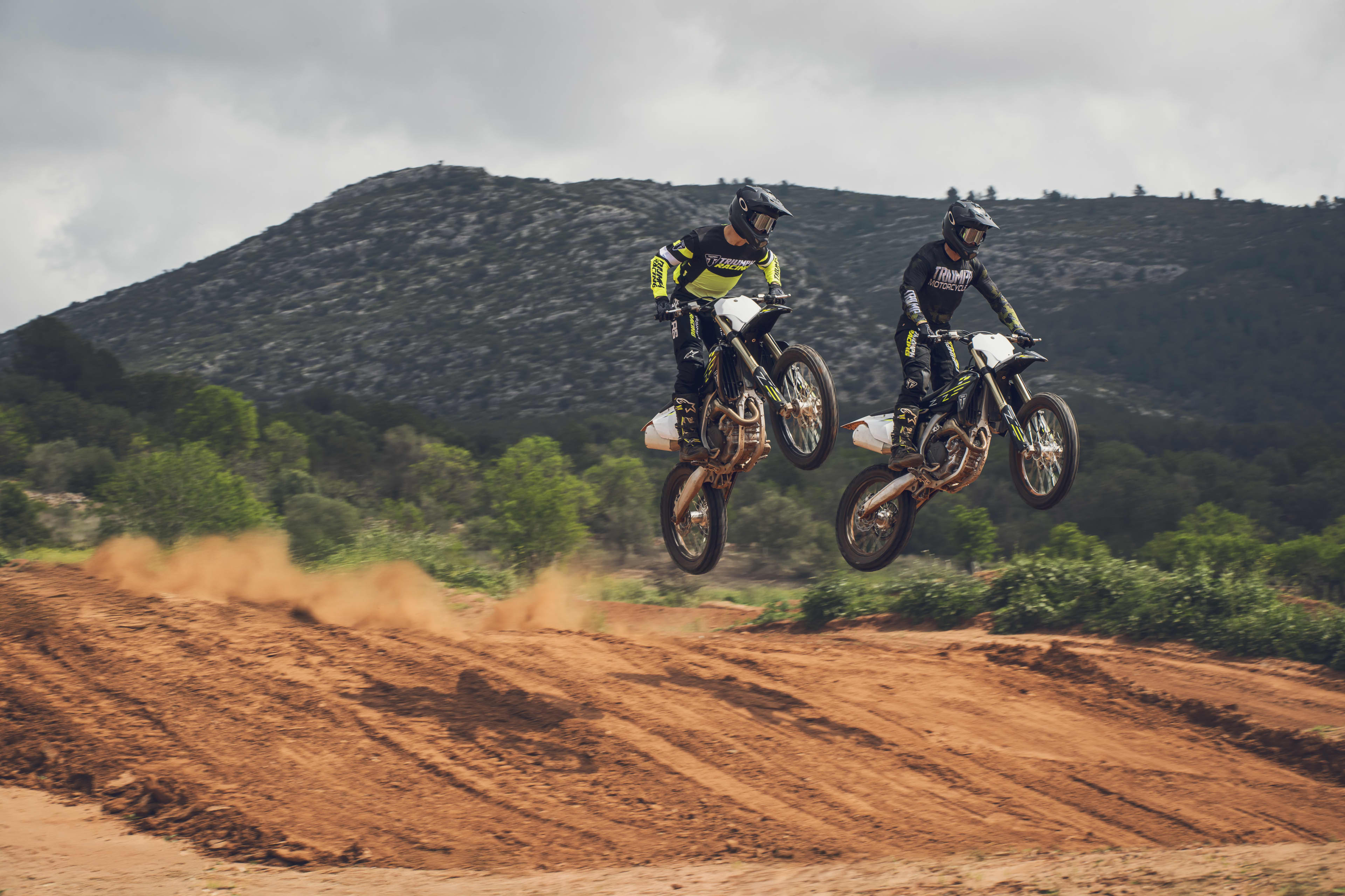Two riders on the Triumph TF 450-X riding over a motocross dirt ramps