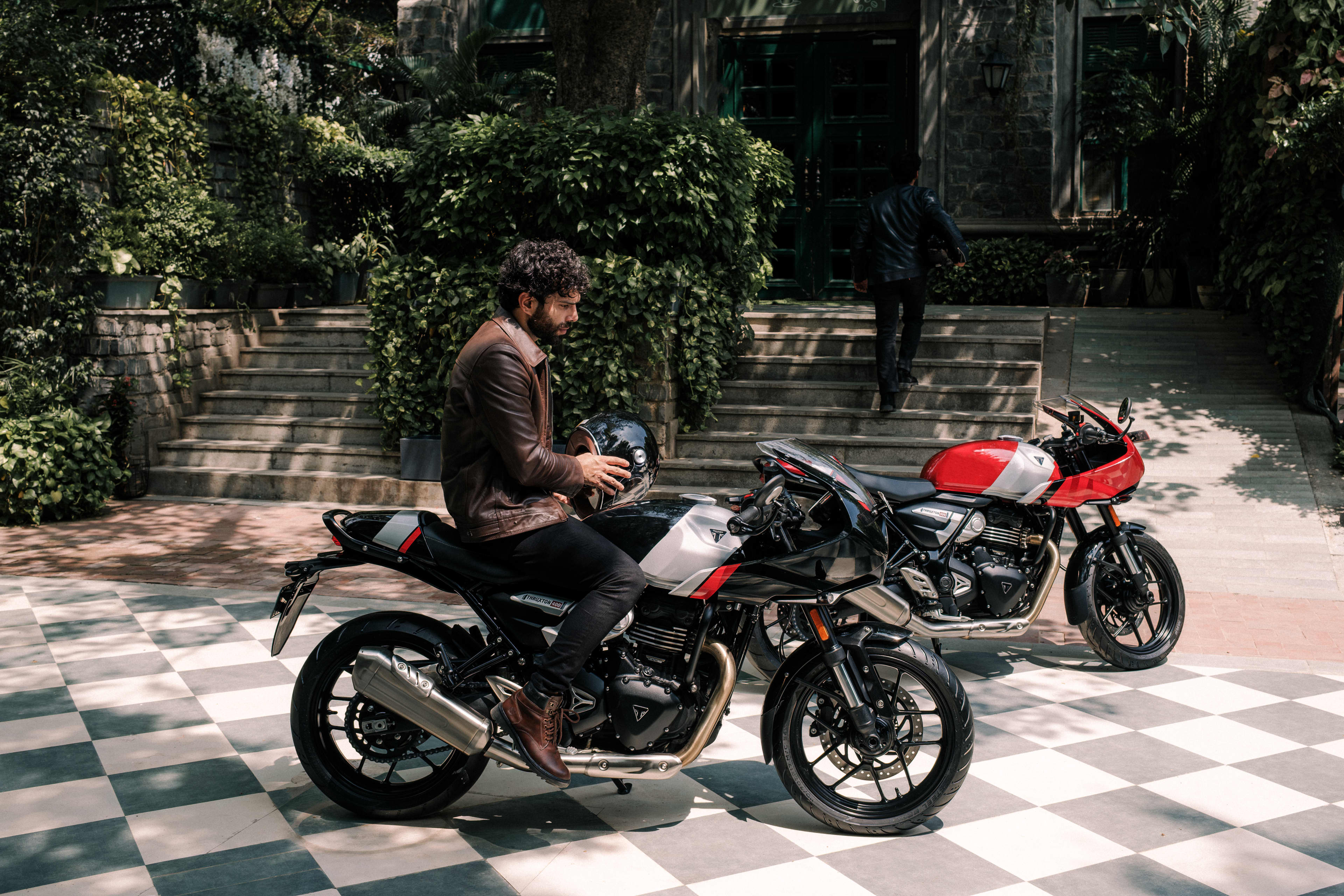 Rider sitting on a Phantom black and Aluminium silver Thruxton 400 with a Lava red gloss and Aluminium silver one in the background