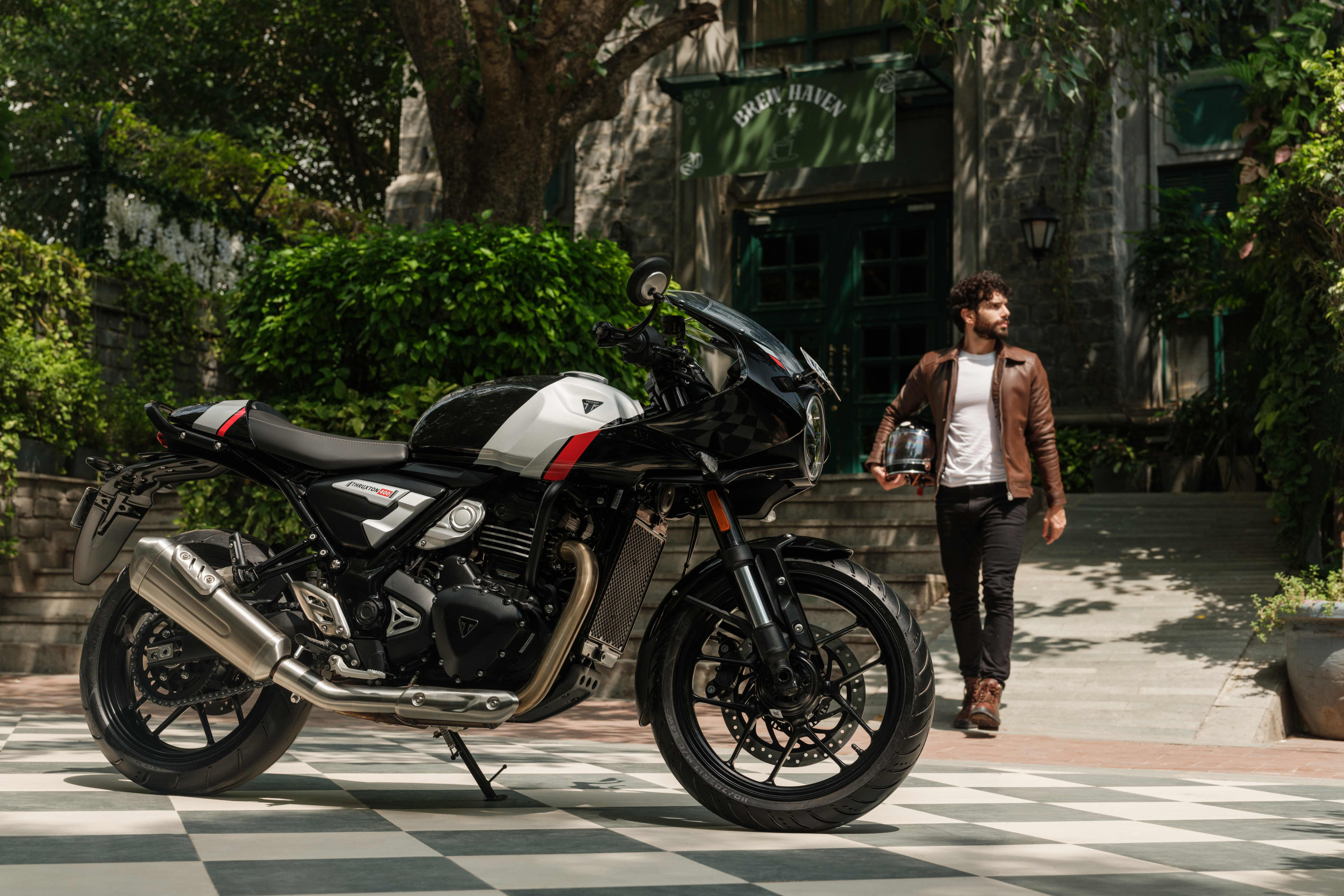 Phantom black and Aluminium silver Thruxton 400 with a rider walking up in the background holding a helmet
