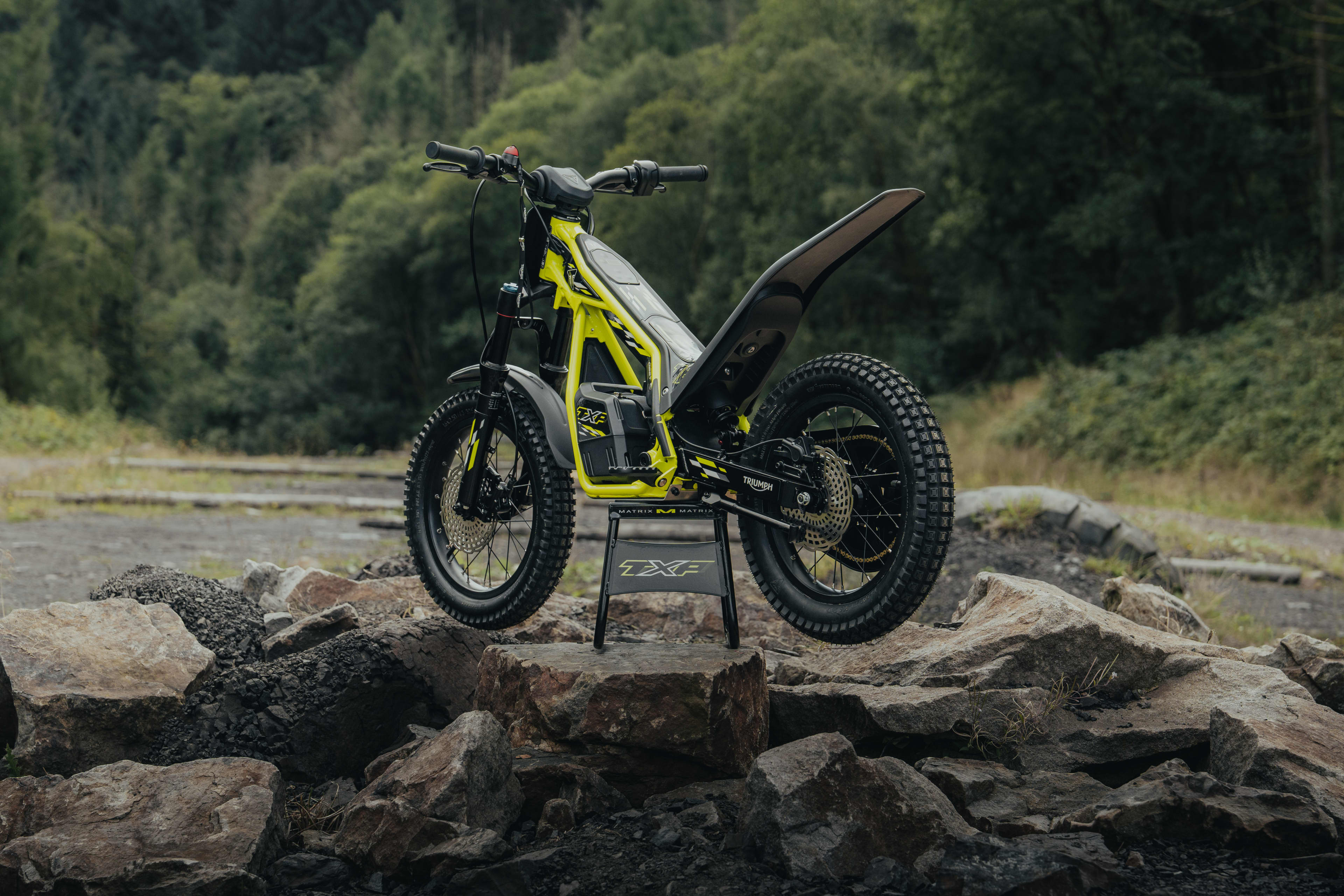 TXP-16 electric bike parked on a rock in a forest setting.