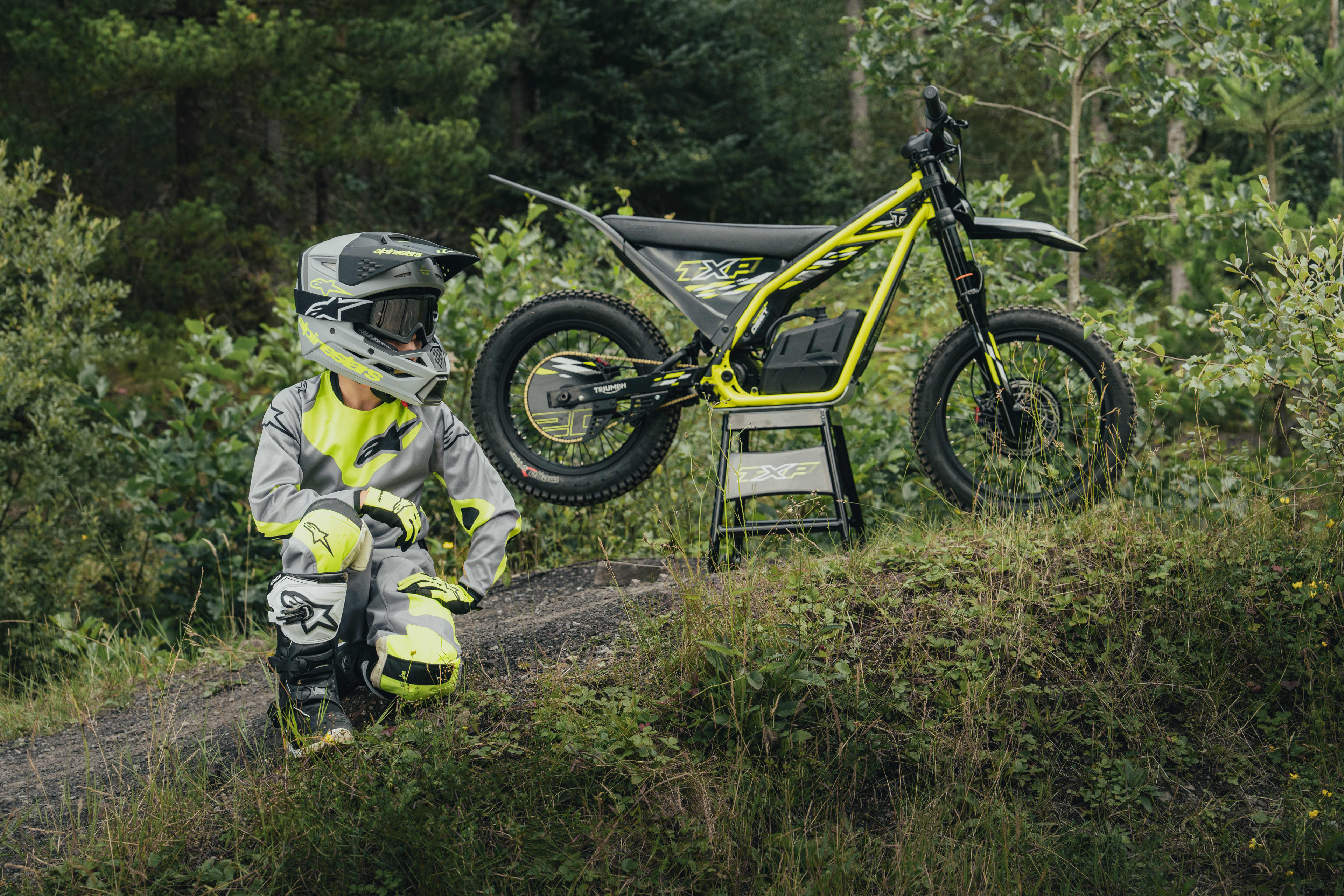 A rider posing in front of the TXP-16 electric bike that is parked up on a bike stand.