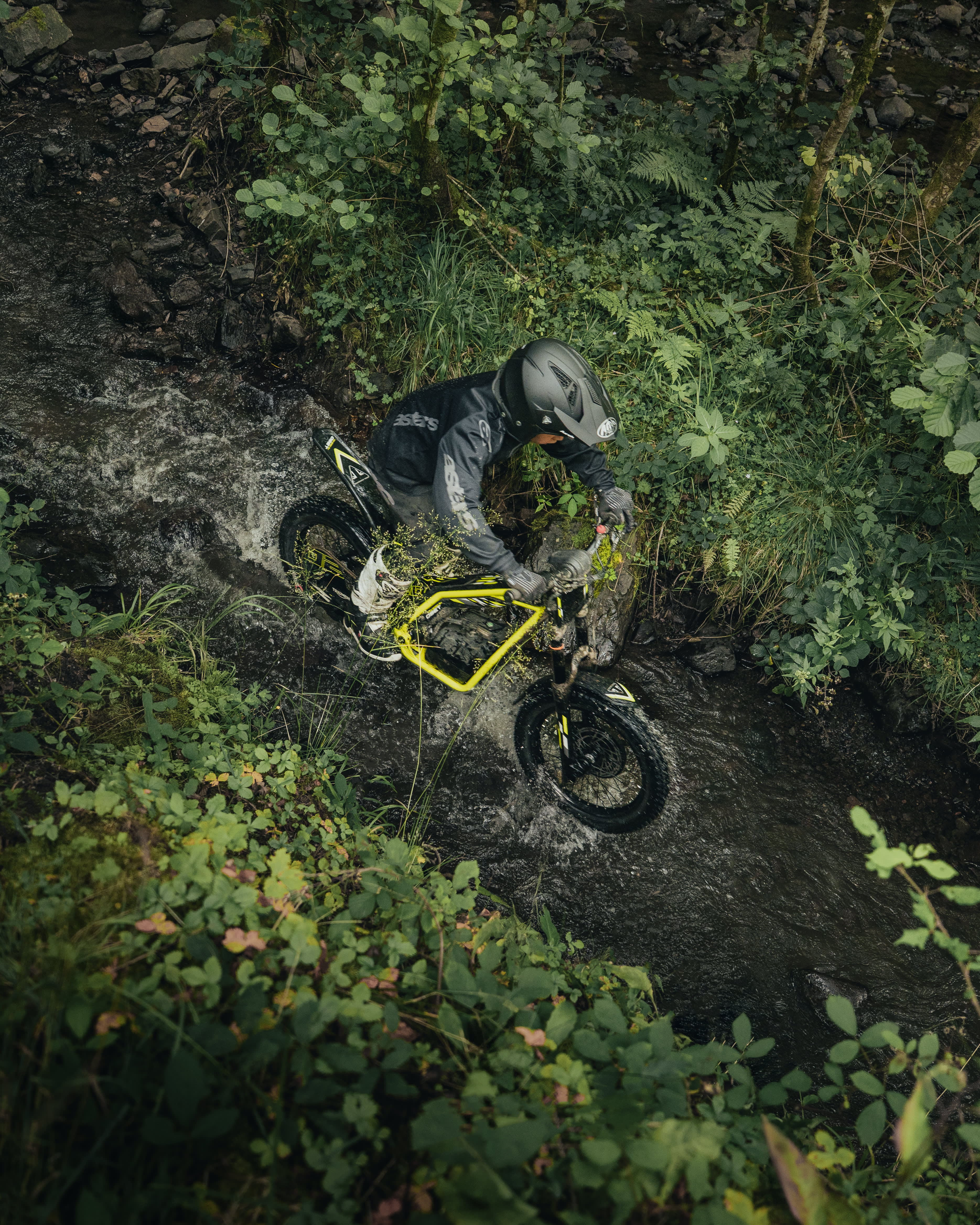 TXP-20 powered by OSET riding through a small stream in a forest.
