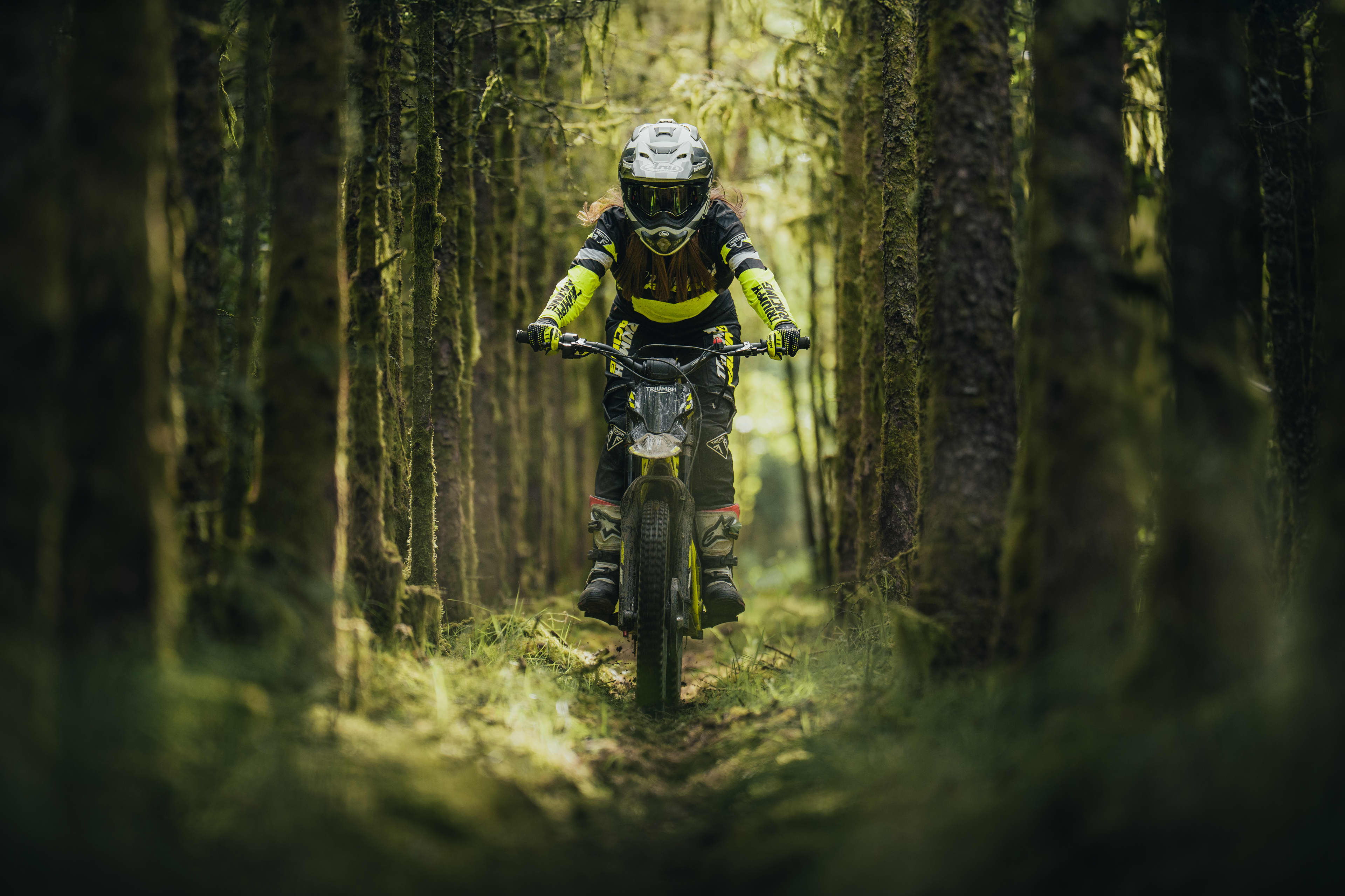 Triumph TXP-24 electric bike going through a green woodland trail.