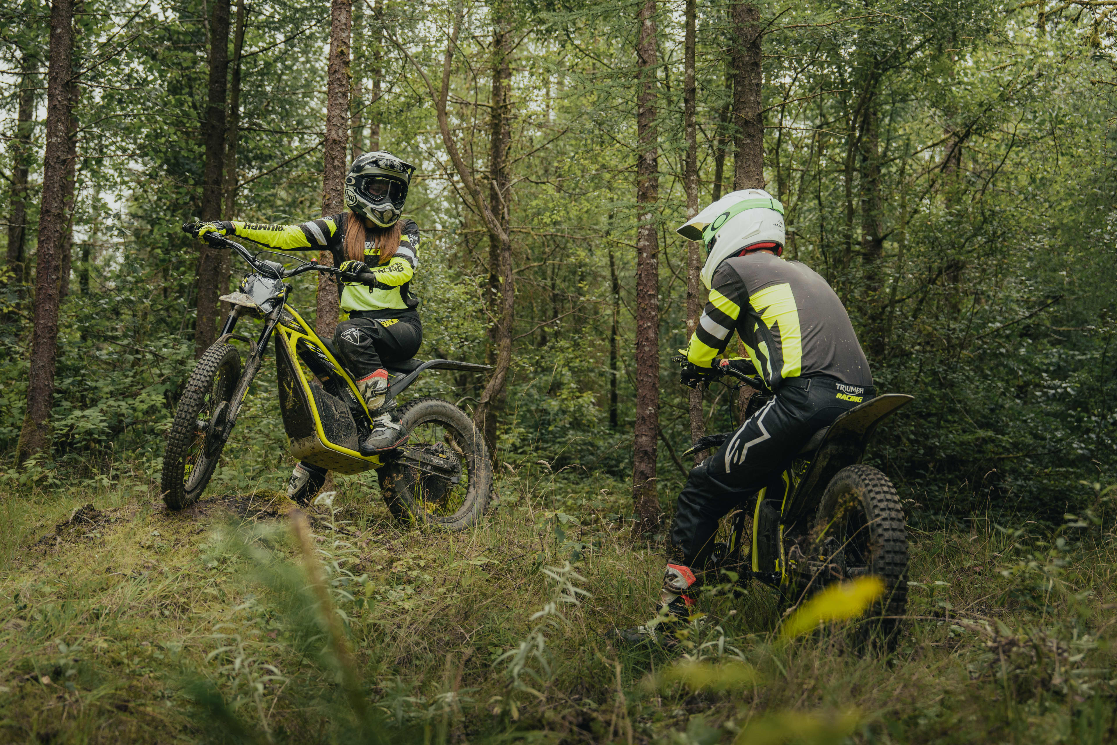 Triumph TXP-24 electric bikes with two riders in the green forest.