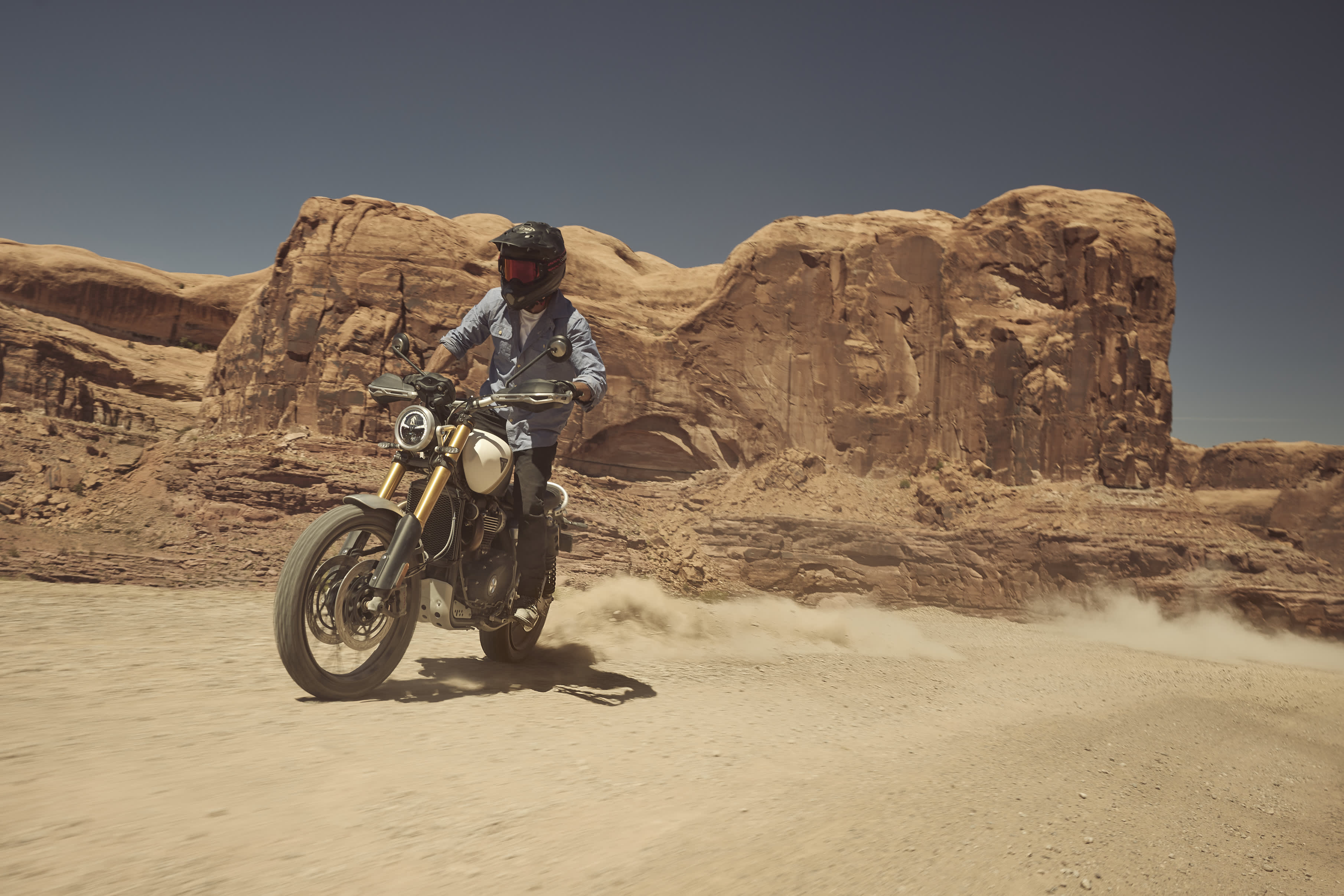 Triumph Scrambler 1200 XE cruising with a rider through a sandy desert
