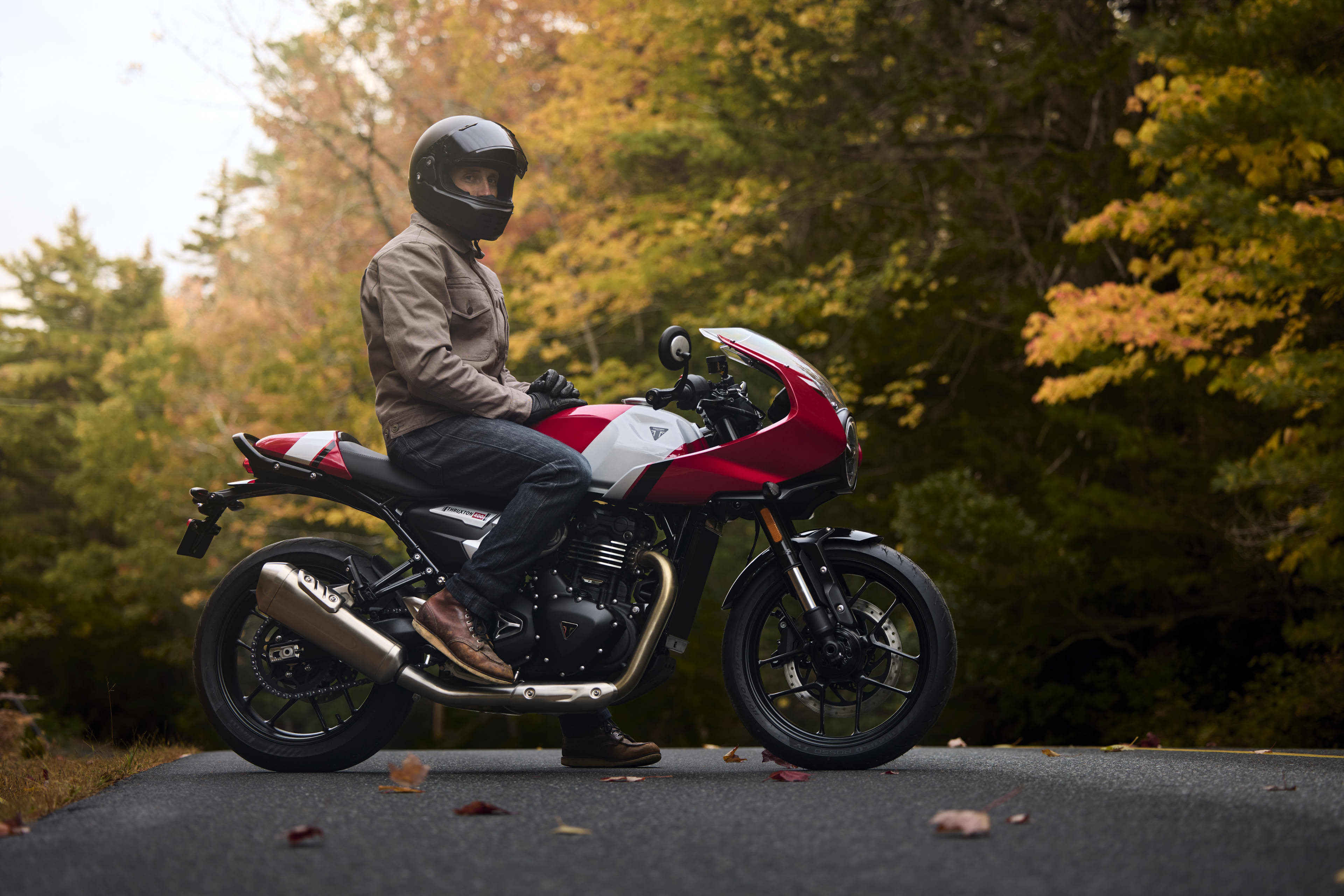 Right hand side of a man sat on a Thruxton 400 parked on a road in a forest