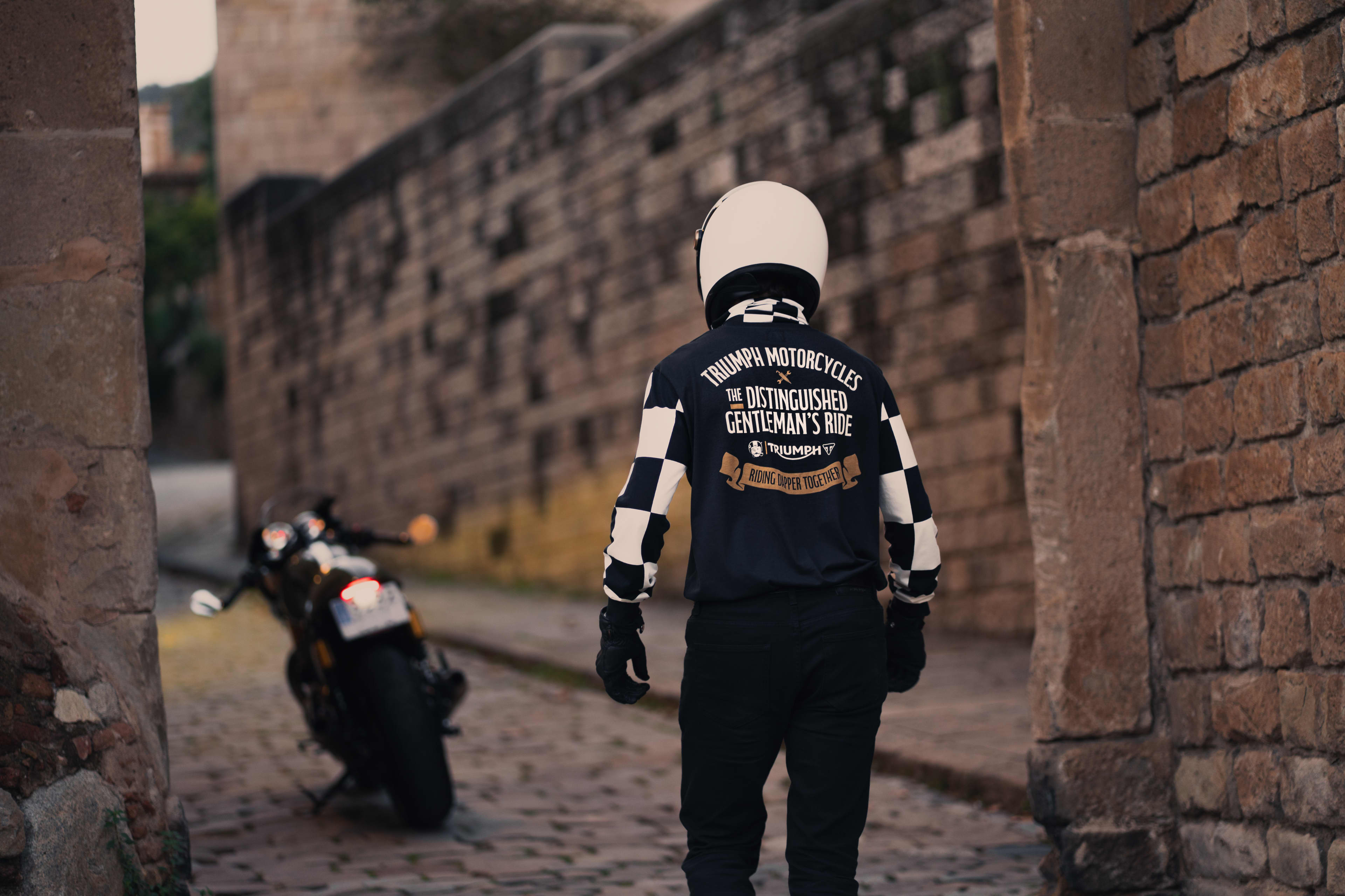 Man walking away towards his bike wearing the Triumph x DGR T-Shirt