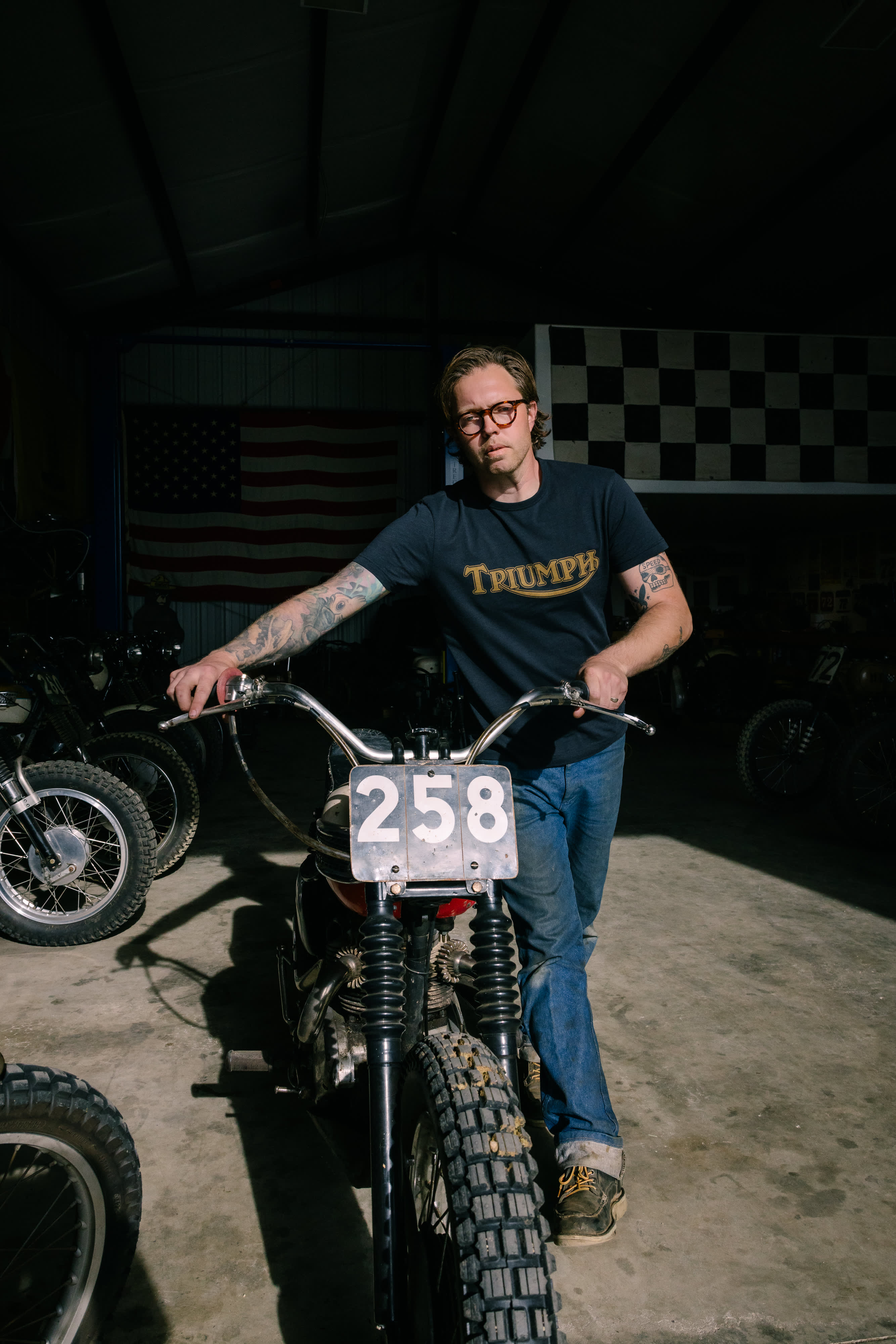 Man walking our of workshop with Triumph Motorbike