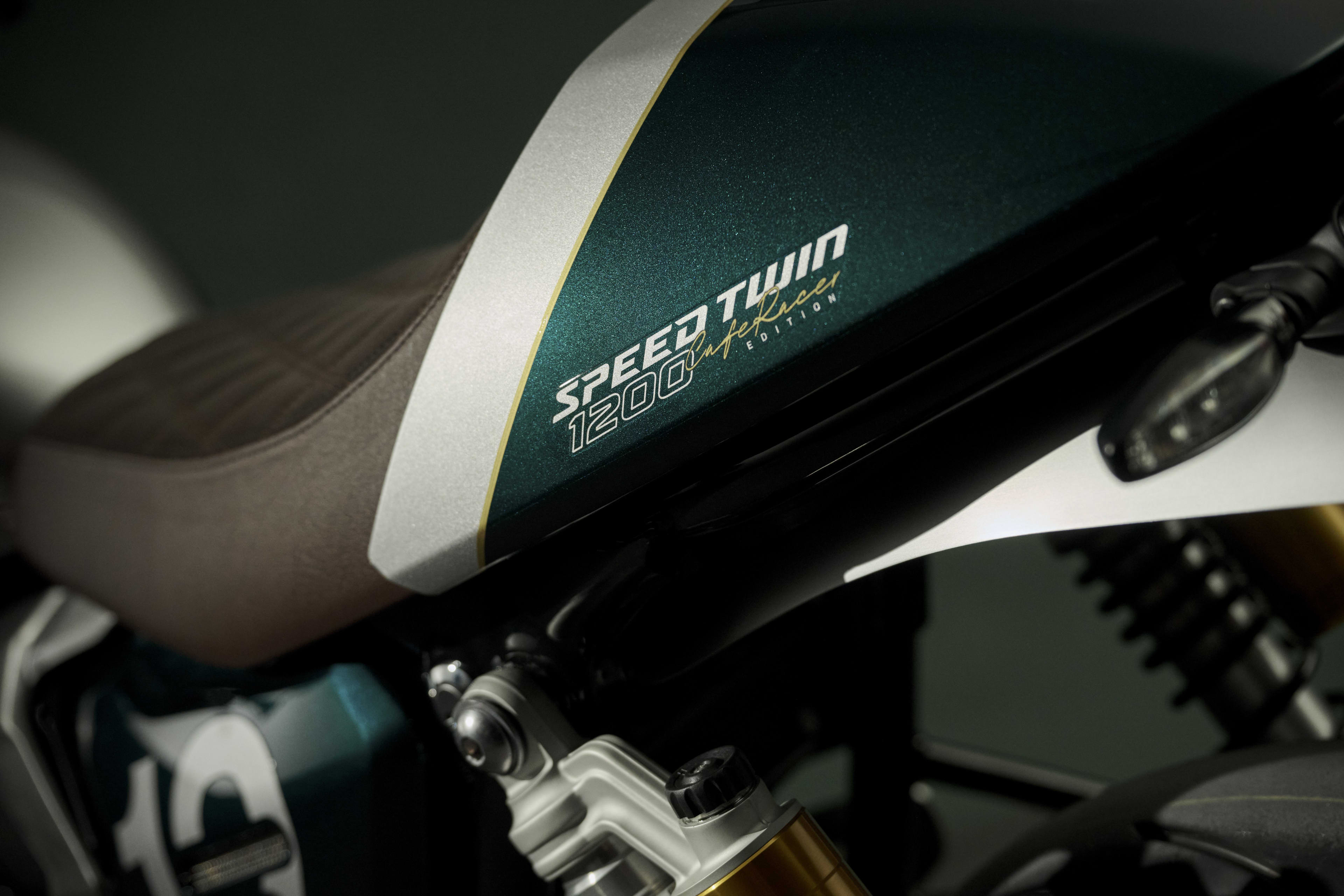 Angled right side action shot of rider on Triumph Speed Twin 900 on a road between hills
