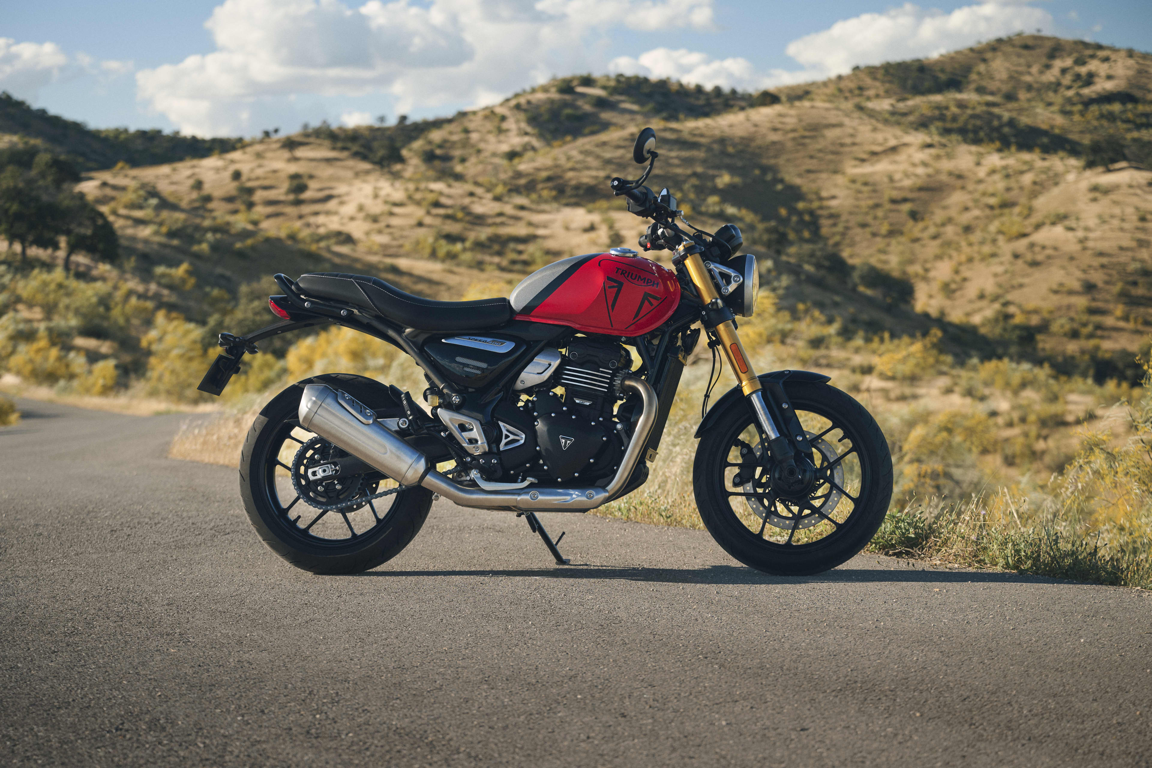 Triumph Speed 400 en Racing Red et Pewter Grey avec un paysage vallonné