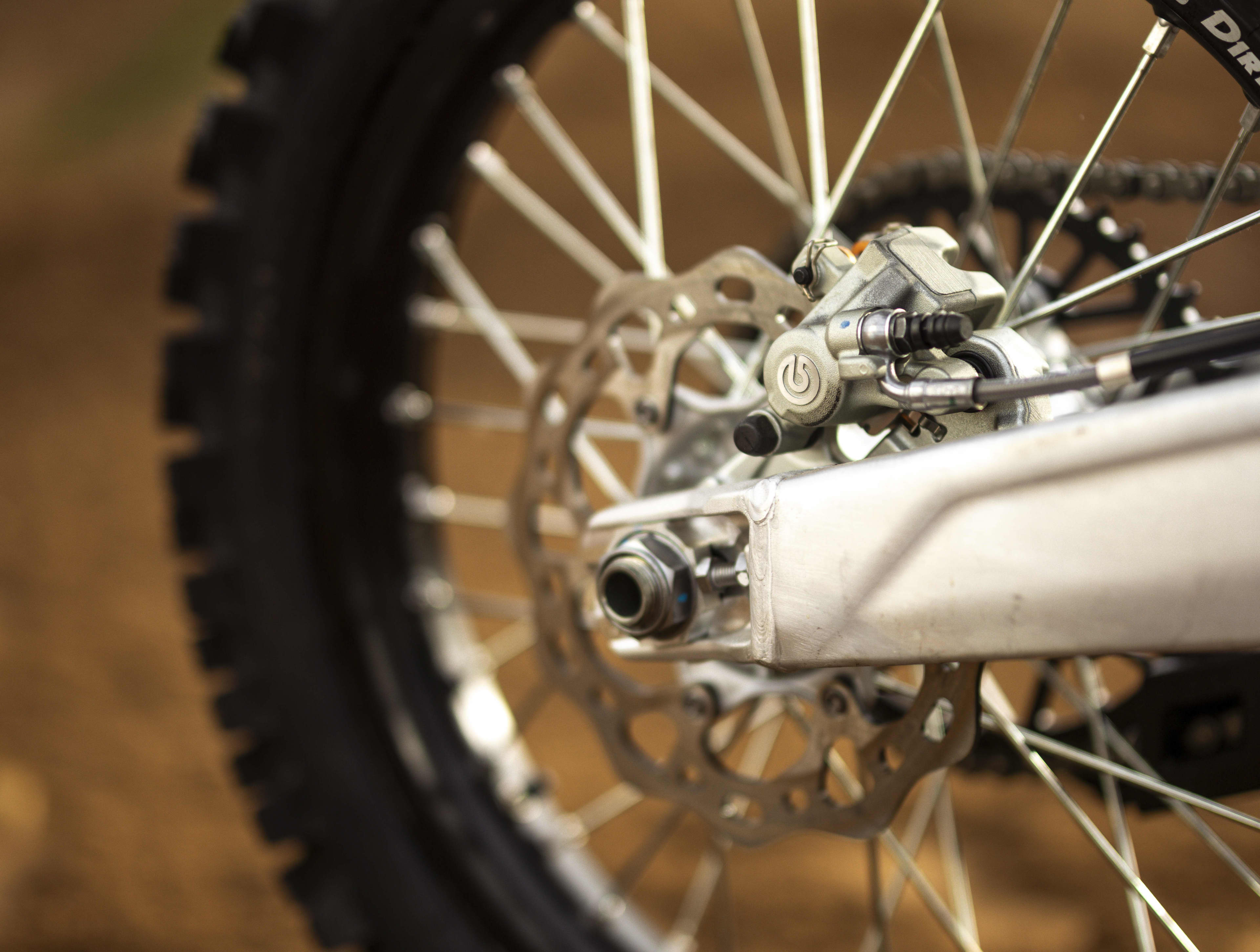 Close-up view of the rear Brembo disc brake and spoked wheel of a Triumph 250-X motorcycle.