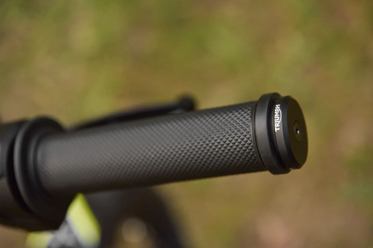 Macro shot of a textured black Triumph TXP-20 handlebar grip with a branded Triumph bar-end cap.