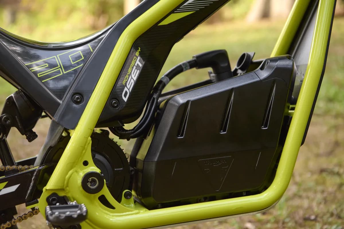 Close-up view of the electric battery unit and neon green frame of a youth Triumph TXP-20 electric trials motorcycle.
