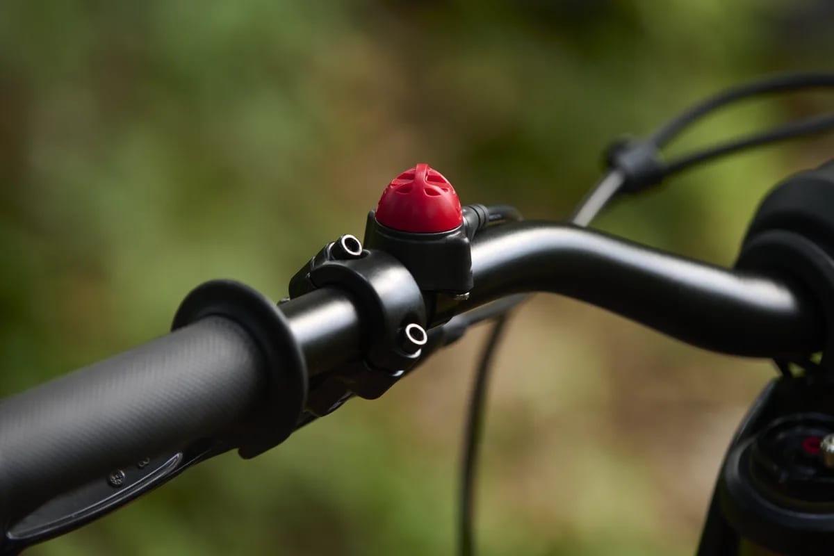 Close-up detail shot highlighting the red power kill switch mounted near the left handlebar grip and brake lever clamp on a Triumph TXP-24 electric motorcycle.
