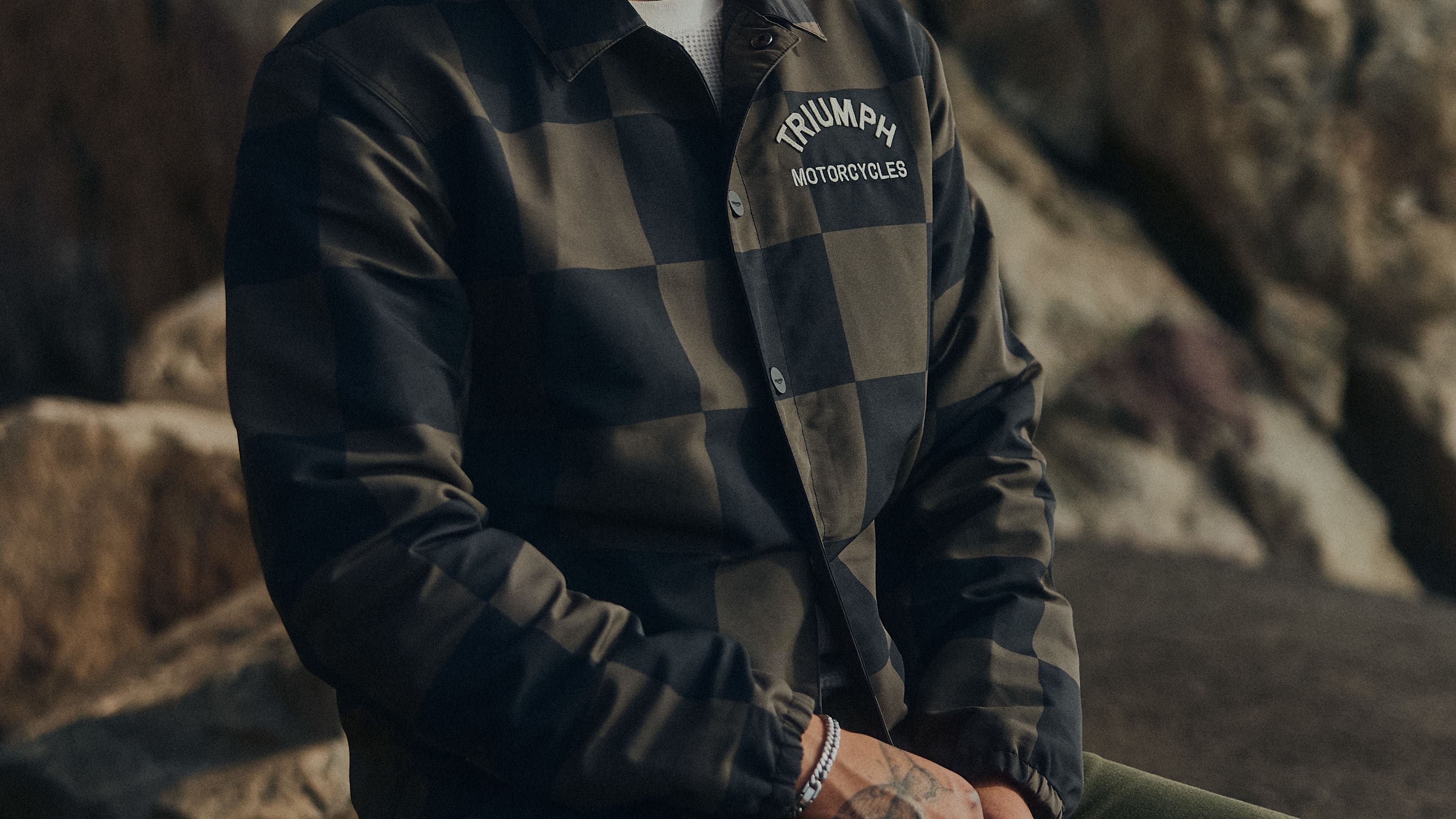 Man sat down wearing the checkerboard coach jacket