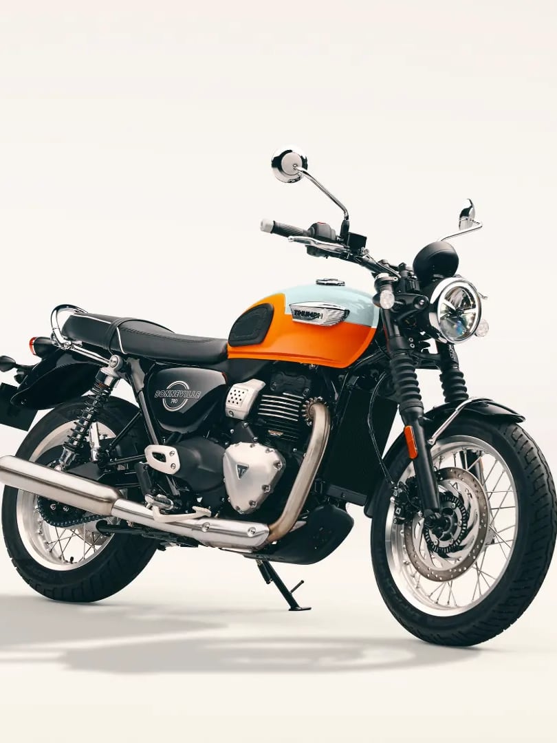 Nouvelle Bonneville T40 Studio shot of an orange and white Triumph Bonneville T40 motorcycle with chrome exhaust parked on a light background.