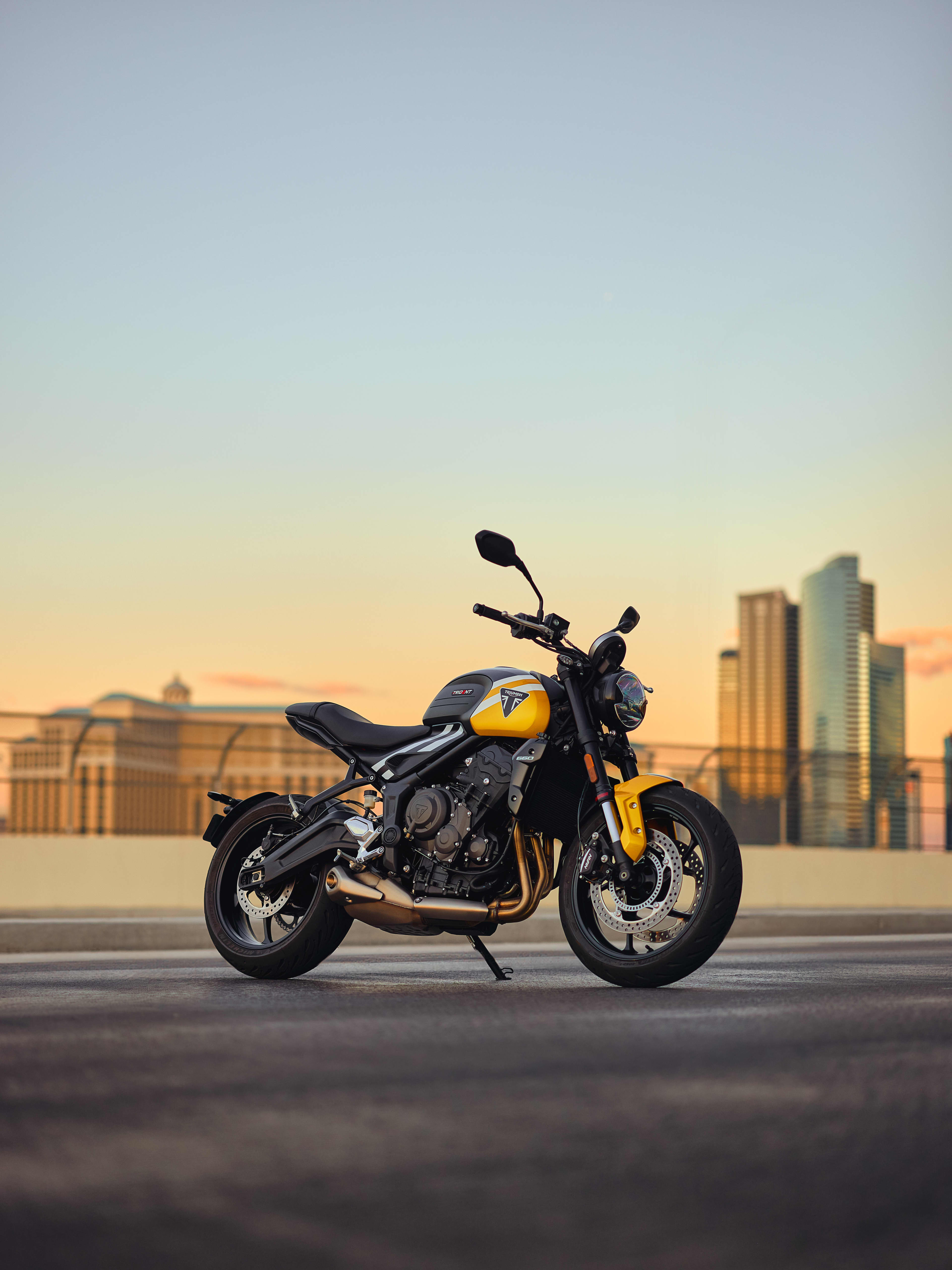 Triumph Trident 660 in Cosmic Yellow in front of city skyline at sunset