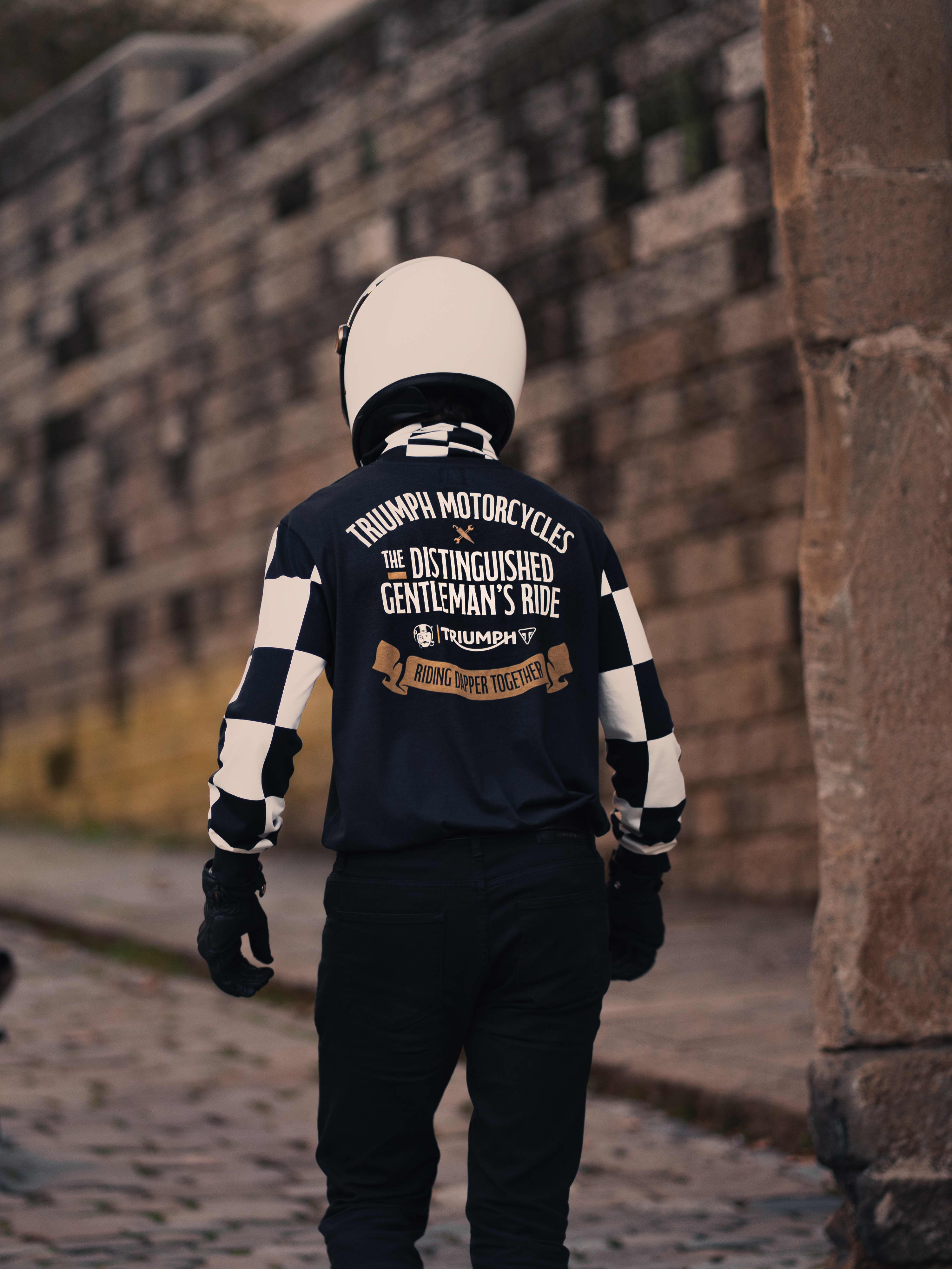 Man stood next to Triumph Motorbike wearing a piece from the Triumph x DGR Collection