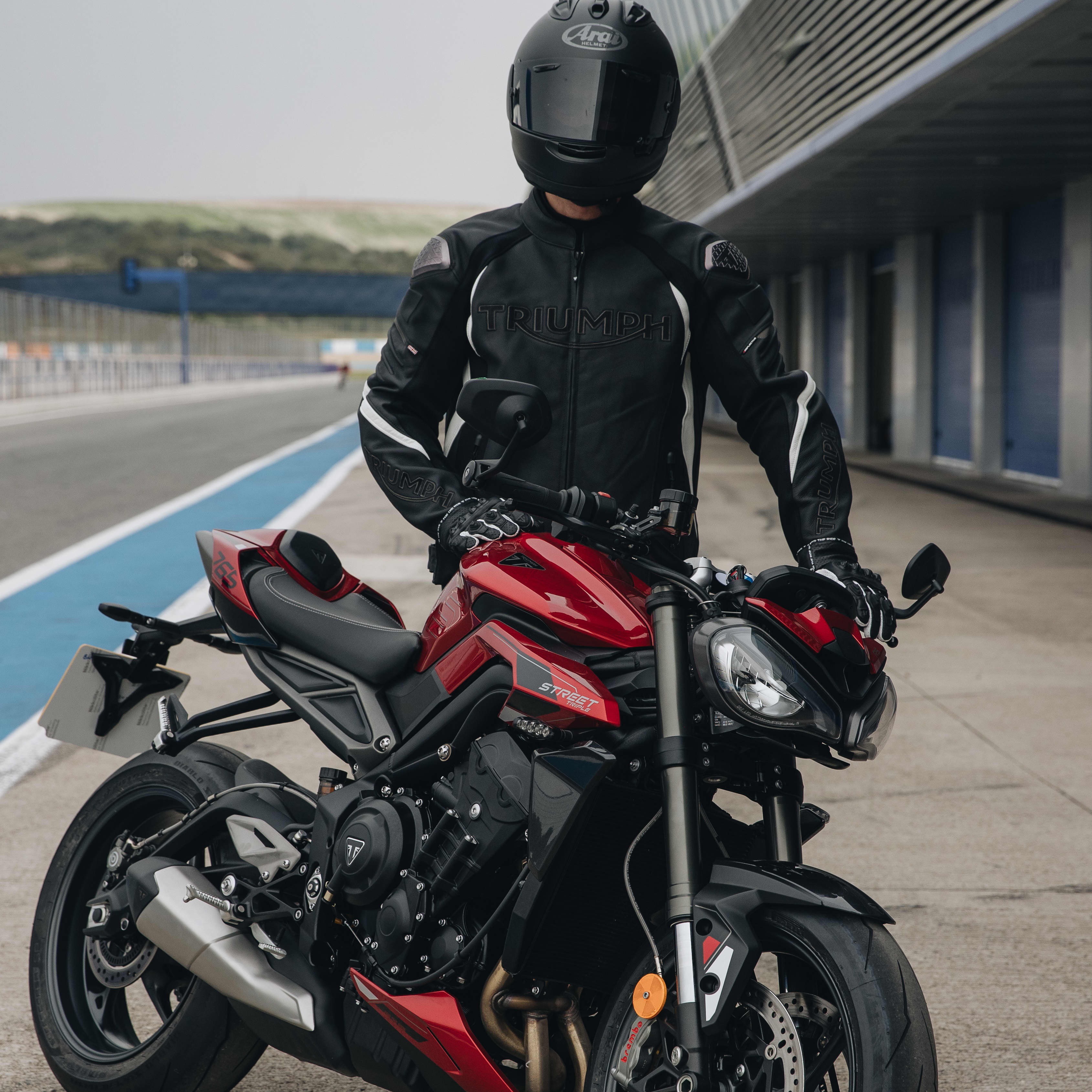Mans back on a Triumph Motorcycle while wearing a yellow Triumph Braddan Jacket